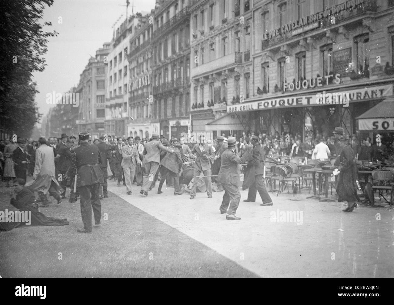 6 , 000 policiers et gardiens de club leur chemin à travers les foules de Paris , femmes battues . Quatre mille policiers utilisant des brumes et des matraques , et 2 , 000 gardes mobiles , brandissant leurs carabines , se sont emparés de leur chemin à travers une foule rassemblée à la tombe du Soldat inconnu à l'Arc de Triomphe à Paris . Les hommes qui ont été attaqués à la police ont été battus au sol et piétinés sur , et même les femmes et les enfants ont été attaqués dans l'accusation . La foule chantait la « marseillaise » lorsque la police a fait son attaque . Photos , la police faisant leur charge dans une foule de combat près d'Arc de Triomphe à Paris . 12 juillet Banque D'Images