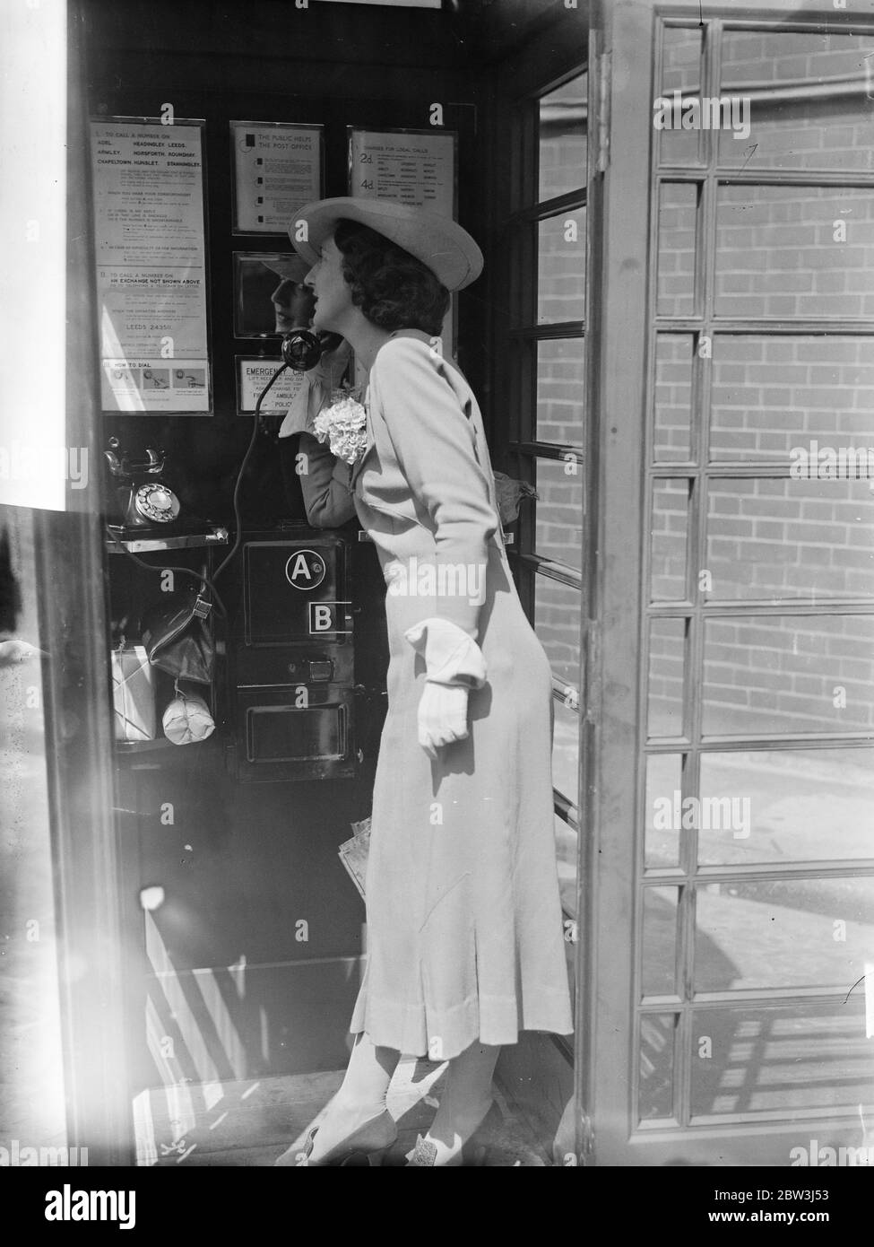 Une dame se tient à l'intérieur d'un kiosque téléphonique. 31 juillet 1935 Banque D'Images