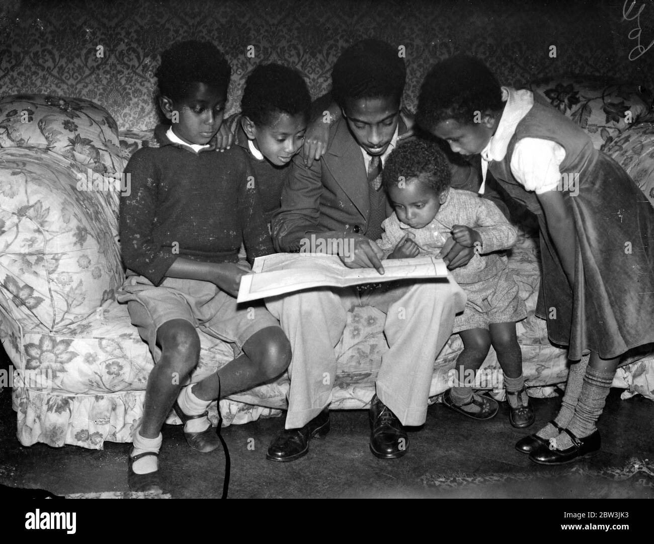 Les enfants du ministre Abyssinian étudient la scène de l'invasion italienne . Joe Martin , fils de 23 ans d'Asaj C Martin , ministre éthiopien à Londres , montrant ses frères et sœurs , le théâtre de l'attaque italienne sur leur pays , sur une carte de la Lgaison Abyssinienne à Londres . De gauche à droite - Charles , Jean , Joseph , David et Léa . 3 octobre 1935 Banque D'Images