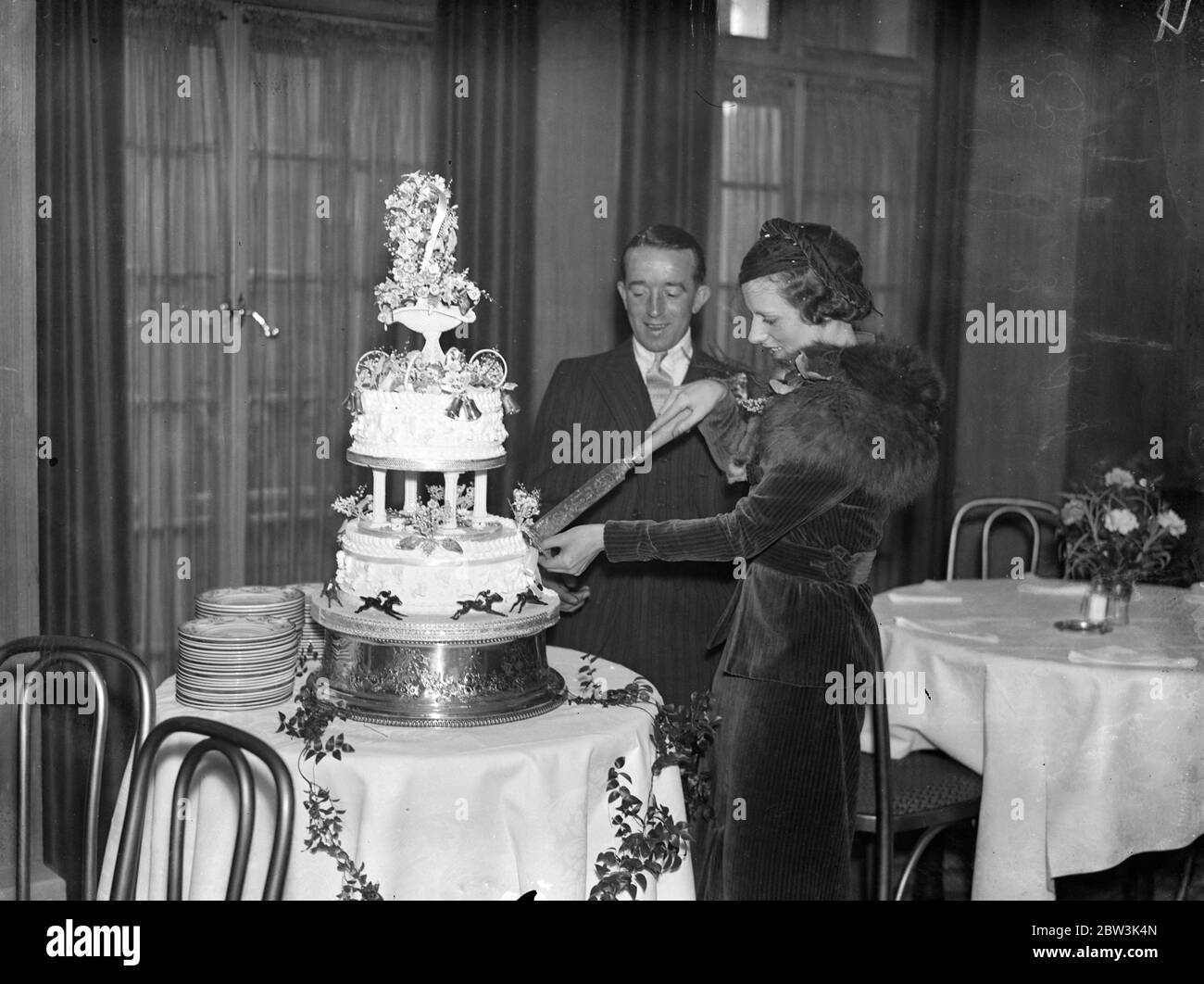 Samuel Wragg et sa mariée ont coupé le gâteau à la réception de mariage . Samuel Wragg épouse Mlle Millicent Maud Smith au bureau de la caisse de Caxton Hall , Londres . Mariée et marié coupant le gâteau . 27 novembre 1935 Banque D'Images