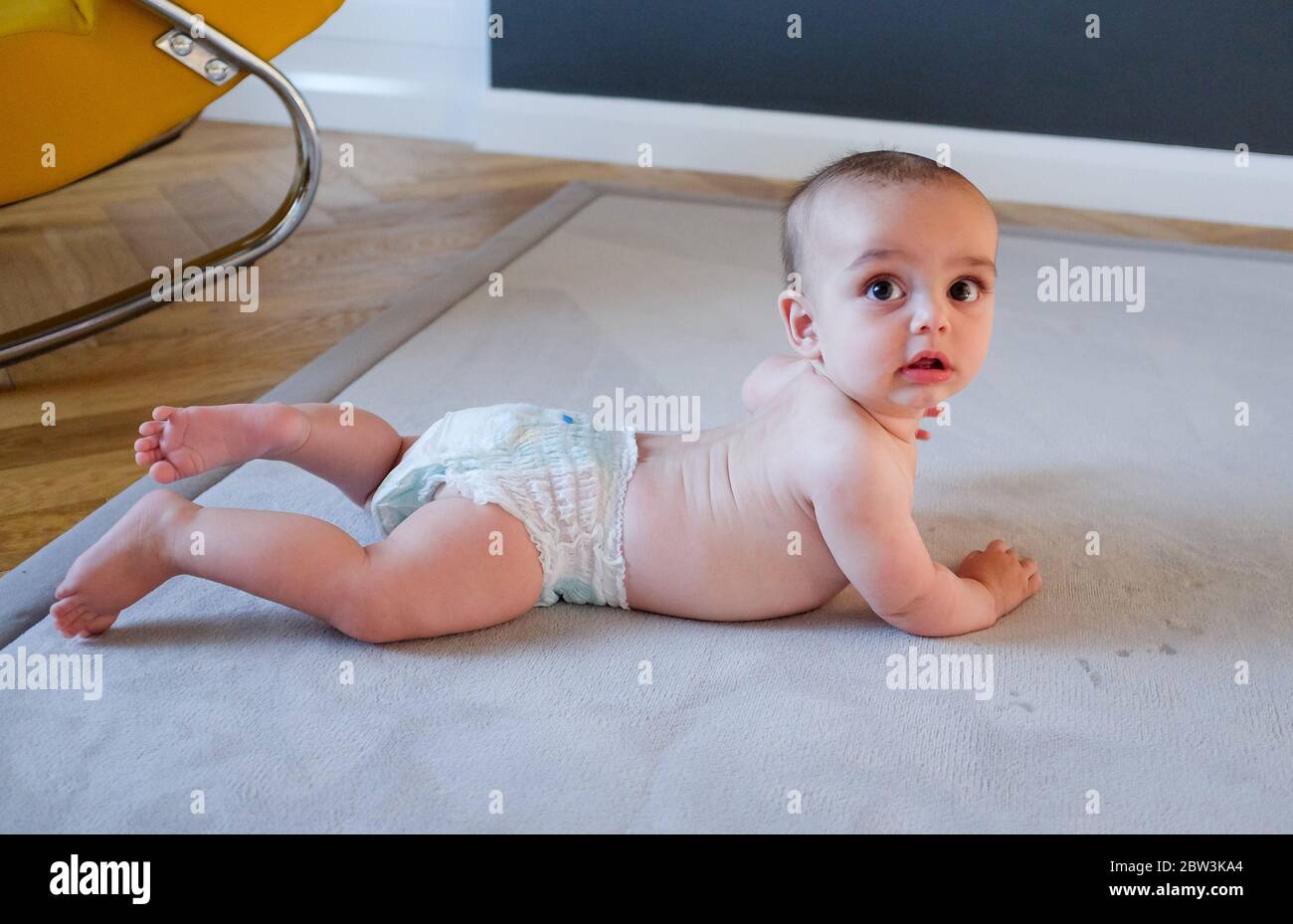 Jeune garçon de 6 mois dans une couches sur un tapis Banque D'Images