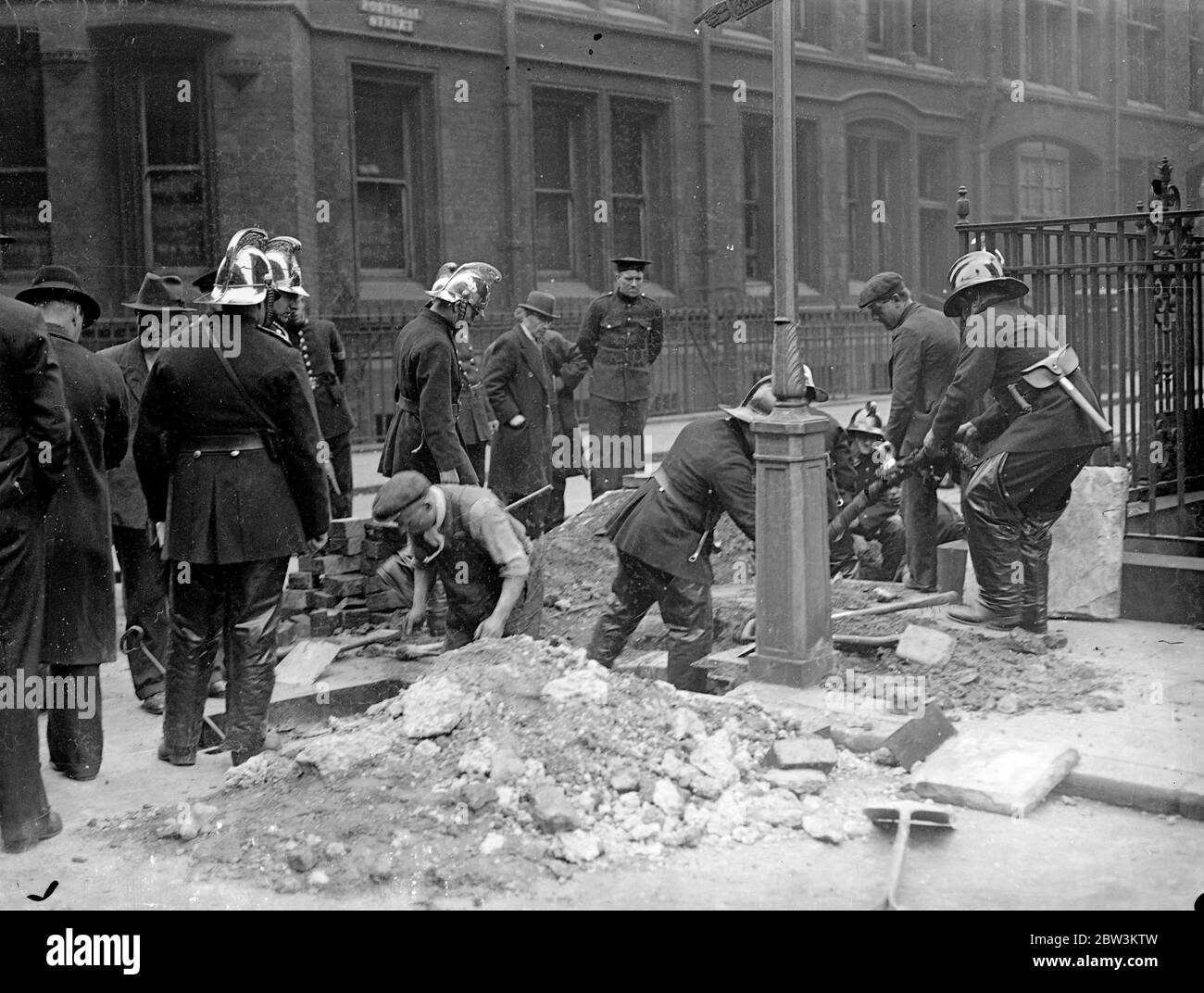 Explosions et incendie suivent la fusion du câble près des tribunaux . Une série d'explosions et de feux ont suivi la fusion d'un câble dans la rue Portugal , près des tribunaux . Les trous d'homme ont été soufflés et le réseau de gaz a également été affecté . Trois moteurs d'incendie ont été appelés . Photos montre , pompiers éteignant le câble de burninig . 7 mai 1936 Banque D'Images