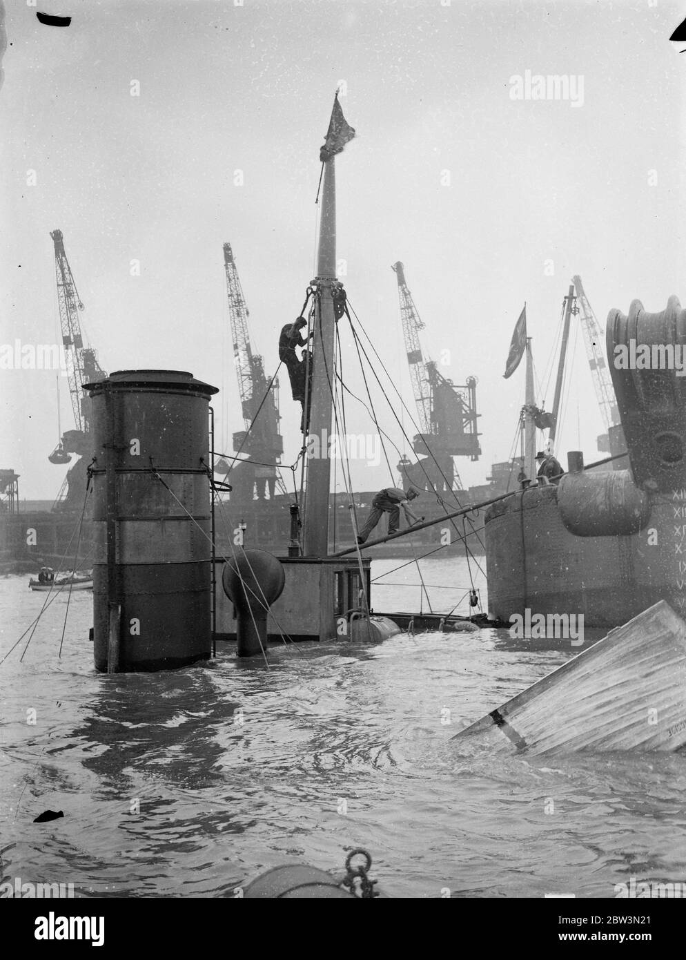 Sauve hommes de P L A préparant le navire à vapeur épaté pour élever le Cragside dans la Thame . Administration du port de London , des briquets d'épave ont commencé des opérations de récupération sur le navire de la compagnie de navires à vapeur Tyne Tans Cragside ( 458 tonnes ) qui a coulé dans Gallions Reach , à l'extérieur de l'Albert Dock après une collision avec 8the S S Ladura ( 9 , 032 tonnes ) Appartenant à la Compagnie de navigation à vapeur de l'Inde britannique . Photos montre , l'équipage de récupération du P L UN épave plus léger préparant le navire à vapeur d'épave pour lever . 9 août 1935 Banque D'Images