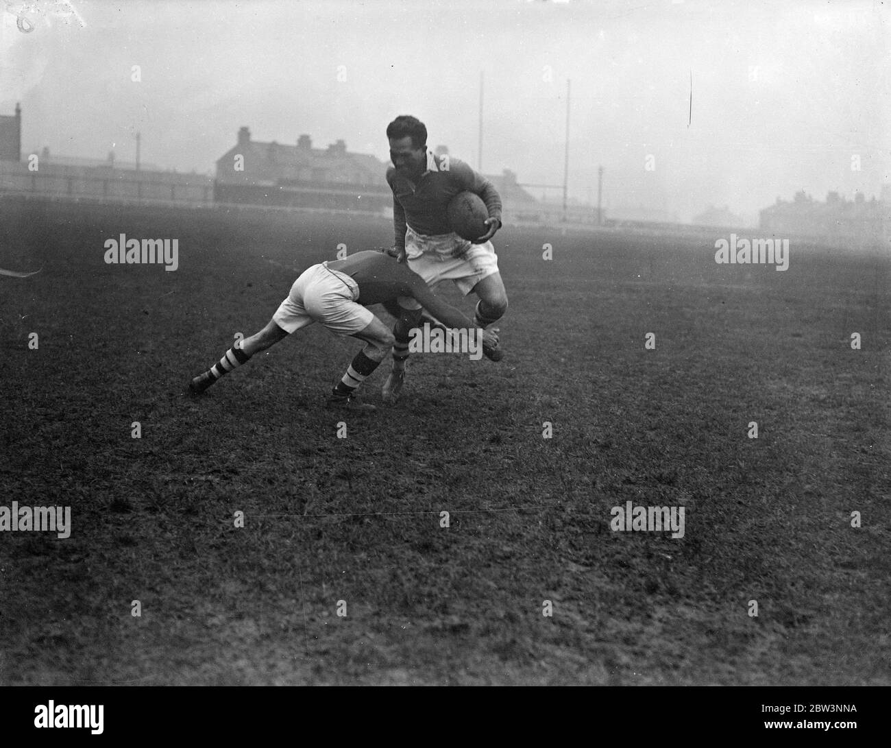 George Nepia , célèbre tout noir , a un procès avant ses débuts dans le rugby de ligue de Londres . George Nepia , considéré comme le plus grand rugby à part entière depuis la guerre , avait un procès au Mitchs Stadium , arrivé à Londres pour jouer au rugby de ligue de football pour le Streatham et Mitcham Club . Nepia a fait sensation en 1924 quand il était membre vedette de ce célèbre tout noir côté . Nepia a l'espoir de jouer tomorow ( samedi ) contre Wigan , mais le décidion dépend du résultat de son rachat aujourd'hui . Photos , George Nepia distribuant un opposant pendant le procès de Mitcham . 13 décembre 1935 Banque D'Images