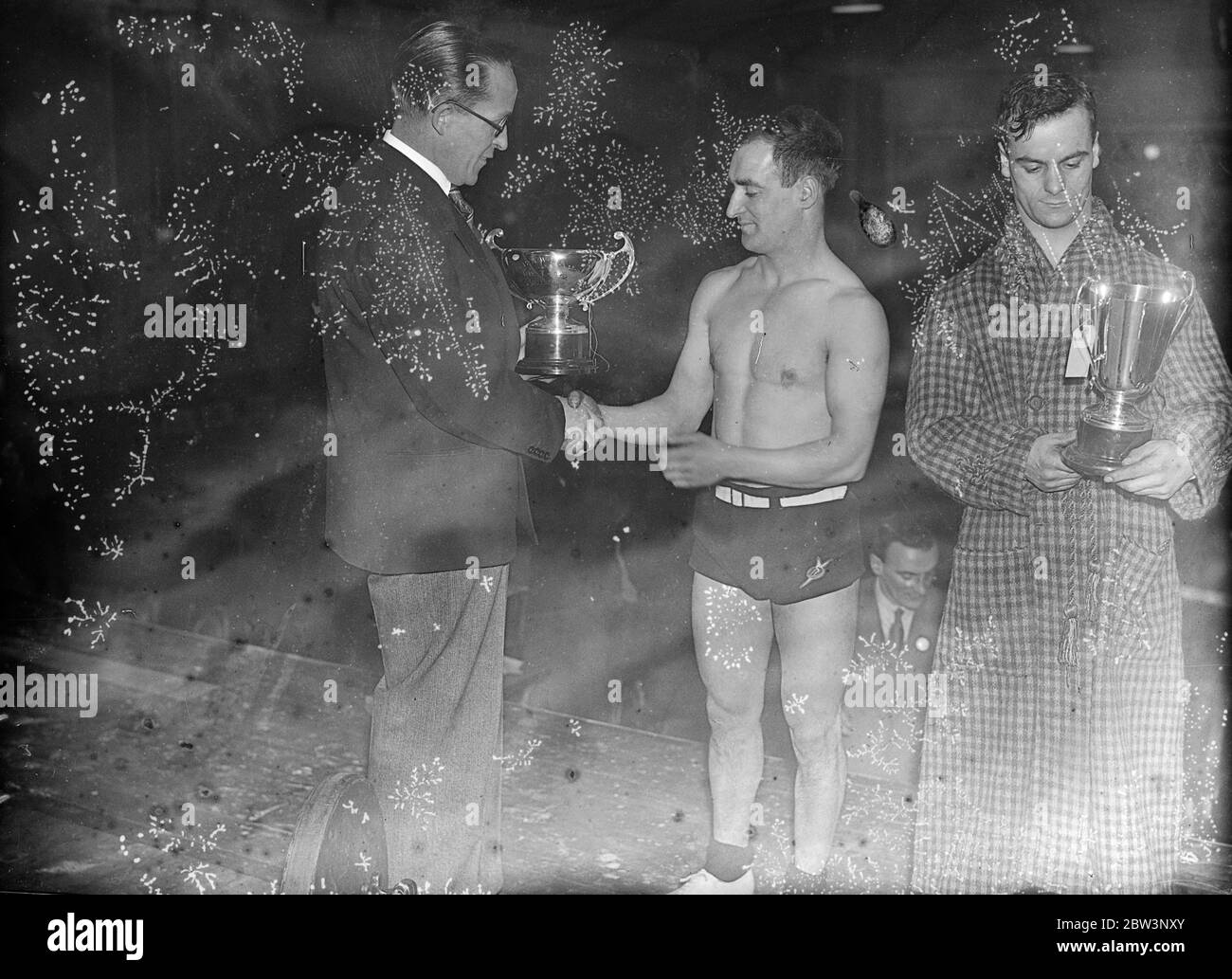 Gagnants du championnat olympique de musculation à Londres . Le championnat olympique britannique 1935 organisé par la British amateur Weight Lifters Association a eu lieu au Lane ' s London Club , King Street . Photos montre E Qualie de Sunderland , vainqueur est la classe bantambalweight avec 217 , 1/2 kilos ( plus de 440 livres ) , recevant sa coupe de M. Wilfred Smith , le célèbre bonesetter et referr . Également dans l'image est NAT Thewlis de Morley ( à droite ) vainqueur dans la classe de poids plume avec 237 1/2 kilos ( environ 500 livres ) 14 décembre 1935 Banque D'Images