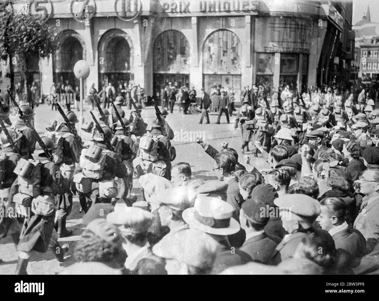 Des troupes d'acier appliquées défilent à travers un attaquant à Liège . Des troupes belges en acier, bien équipées et en train de se faire accompagner à Liège dans une tentative de calme de la ville , ont dû marcher entre les lignes de grévistes qui ont donné le salut communiste et ont crié ' Laissez-les rejoindre ' . Les grévistes et la police ont affronté plusieurs fois dans la ville , au centre de la zone de grève , où plus de 85 000 hommes sont sortis . Les gangs sillent les rues . On craint maintenant que la grève se propage de la province de Liège , dans tout le pays et qu'un million de travailleurs soient impliqués . Photos spectacles , troupes en acier hélifait mar Banque D'Images