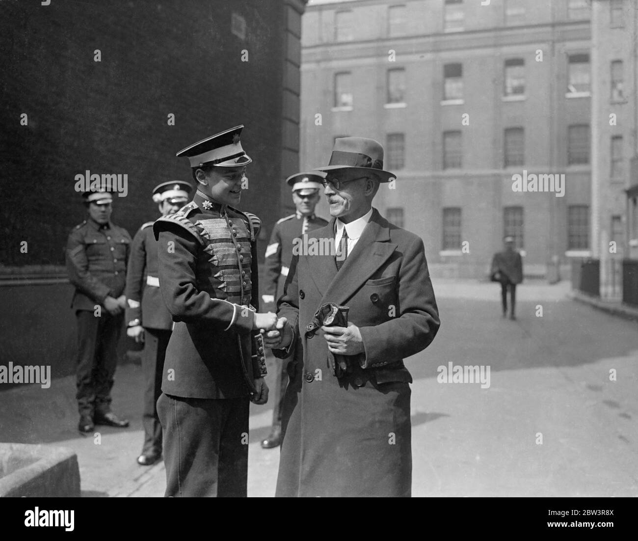 Coldstream Guards musicien qui prend sa retraite après 51 , 1 / 2 yeaars service . Le Lieutenant général Sir H E Codrington , qui a distribué des roses aux Guardsmen , a présenté l'emblème au musicien Kemble et l'a félicité pour l'achèvement de son service . Photos , musicien Tom Kemble , qui prend sa retraite après 51 , 1 / 2 ans de service , félicité par le musicien J Ellory , 16 ans plus jeune membre de la bande régimentaire . 22 avril 1936 Banque D'Images