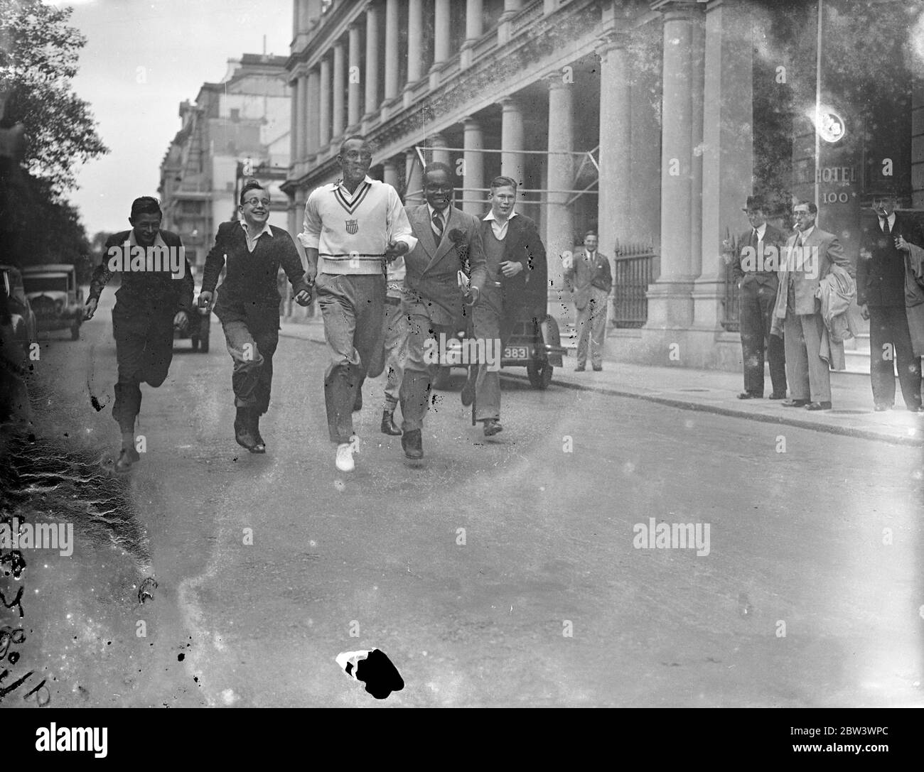 Jesse Owens fait de London Street son circuit . Jesse Owens , le ' Black Panther ' et vainqueur des médailles d'or olympiques de 3 , a présenté une démonstration aux garçons de Londres qui l'ont assiégé pour la corruption de ressources à son hôtel après son arrivée d'Allemagne . Owens doit participer à l'Empire britannique , à l'athlétisme des États-Unis à la ville Blanche ( samedi ) . Photos, Jesse Owens courant avec des garçons à l'extérieur de l'hôtel de Londres. 14 août 1936 Banque D'Images