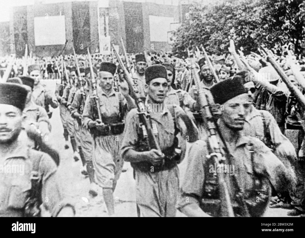 Plus de troupes marocaines quittent Burgos pour le front de guerre civile. Une attaque contre Madrid est attendue. D'importants détachements de troupes marocaines et de légionnaires étrangers ont quitté Burgos , le quartier général des rebelles en Espagne pour renforcer les insurgés . On pense qu'ils doivent participer à la grande marche sur Madrid qui est actuellement organisée par le général Mola , chef rebelle du Nord . Photos : armes soulevées dans le salut fasciste alors que les troupes du Maroc marchaient hors de Burgos . 25 août 1936 Légende originale de négatif Banque D'Images