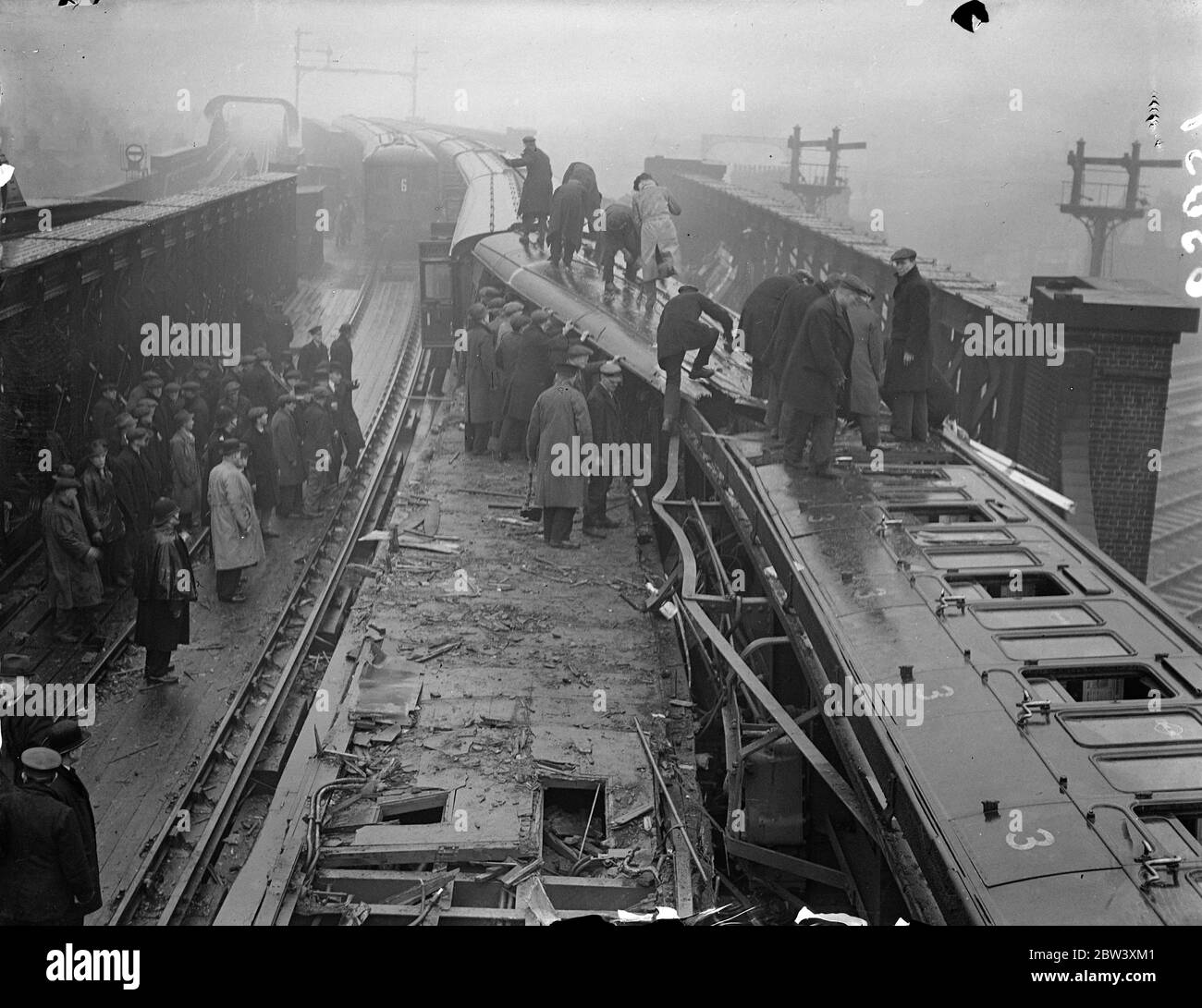 Trois personnes étaient connues pour être mortes, d'autres auraient perdu la vie et beaucoup ont été blessées lorsque deux trains électriques ont heurté le pont de Fourspan entre Queens Road et la gare de Battersea Park. Les cars étaient télécopés et rentournés. Photos : des hommes au travail sur l'épave. 2 avril 1937 Banque D'Images