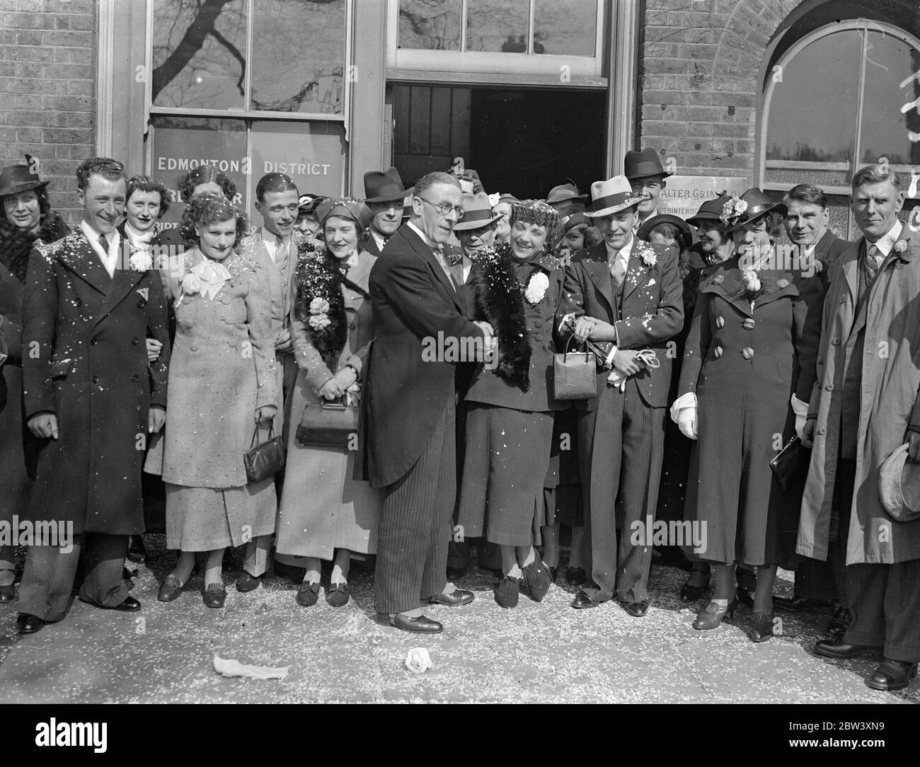 60 mariages ont été réalisés aujourd'hui au bureau d'enregistrement de White Hart Lane, à Tottenham. C'est le jour de pointe de la ruée des vacances de Pâques où 30 cérémonies seront exécutées. Séances photo-M. Walter Grimaldi, le registraire, félicitant les couples après leur mariage. En 25 ans, M. Grimaldi a réalisé 20,000 mariages, considérés comme un record pour le pays. 27 mars 1937 Banque D'Images