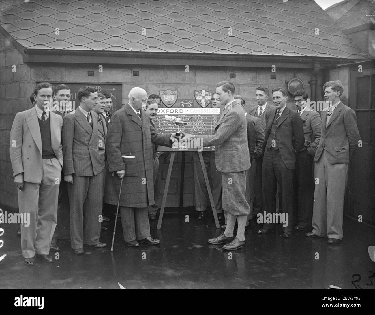 Cambridge a battu Oxford lors d'un match annuel de tir à la carabine à Londres. L'université de Cambridge a battu l'université d'Oxford de 785 points contre 777 dans le 12e match annuel de tir à la carabine pour le trophée défi Heslop tenu sur la gamme de tir de toit de W H Smith and son, Ltd., Strand House, Portugal Street, Kingsway. Expositions de photos : le Lieutenant général Sir Alfred Codrington se secouant la main avec D J Ramsay, le capitaine de Cambridge après avoir présenté le trophée. L'équipe gagnante est sur la droite. 25 février 1937 Banque D'Images