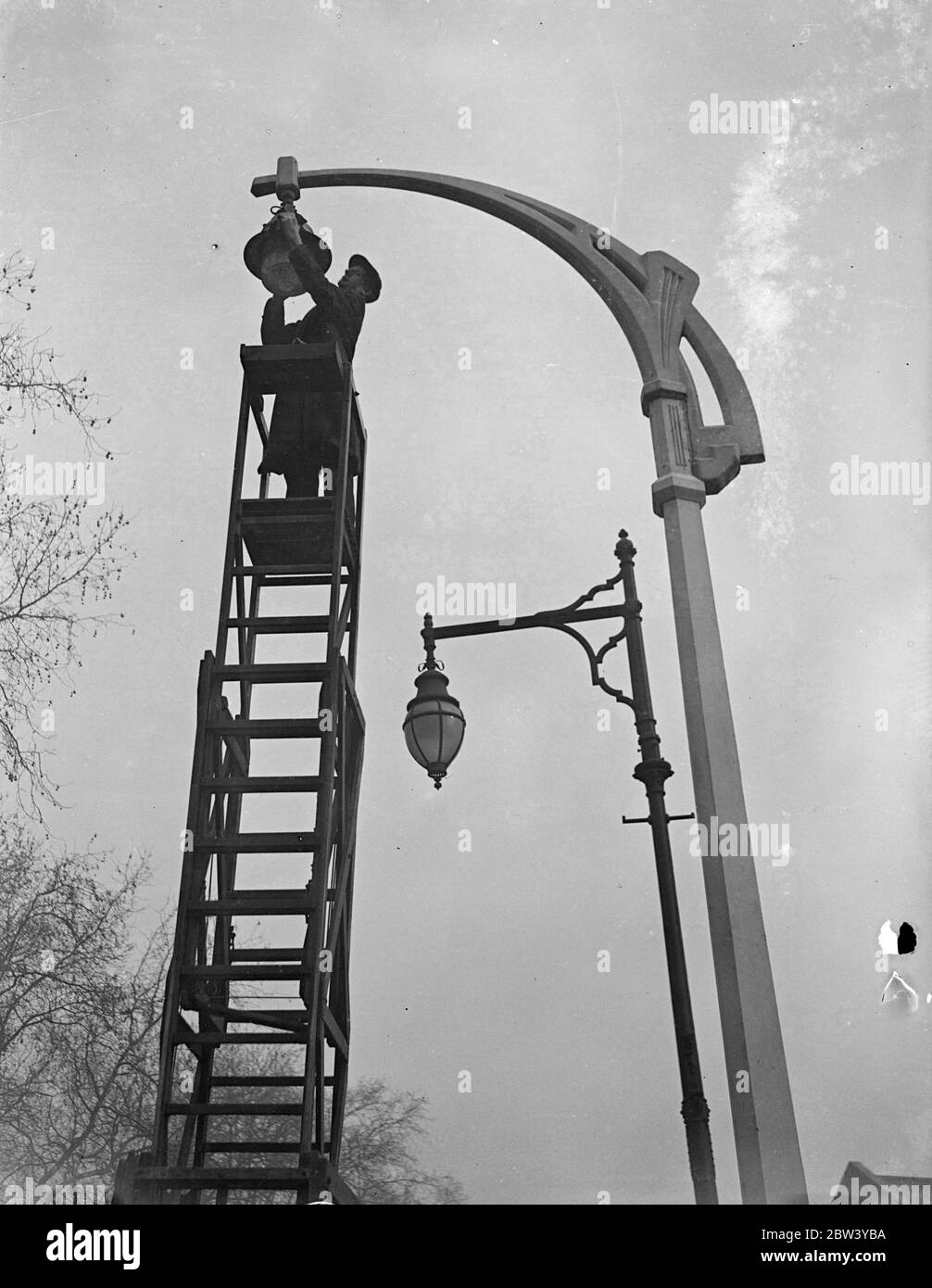 Nouvelles lampes pour l'ancien à Fulham. De nouvelles normes intelligentes de lampes sont érigées dans le chemin New King, Fulham, dans le cadre du projet du ministre des Transports visant à améliorer l'éclairage de la rue. Photos : l'une des nouvelles lampes est située sur la route du Nouveau Roi, avec l'un des anciens types en arrière-plan. 4 mars 1937 Banque D'Images