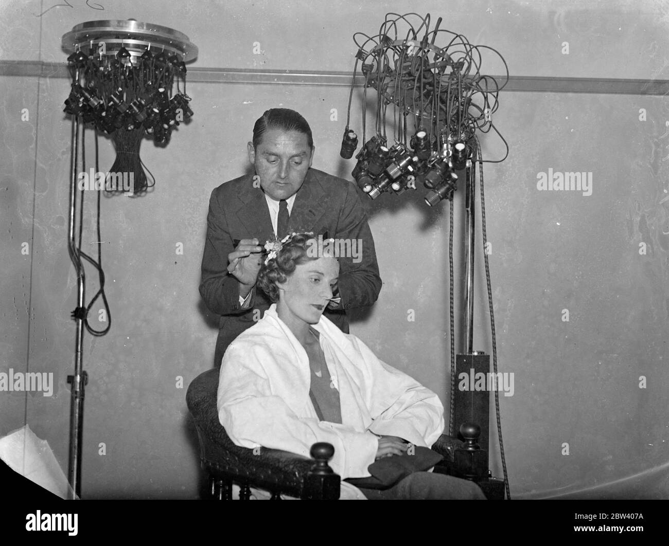 Nouvelles créations pour salon de coiffure . De nombreuses nouvelles coiffure saisissantes et les derniers appareils de culture de beauté seront en vue à la Foire de cheveux et de beauté qui aura lieu à Olympia , Londres la semaine prochaine . Photos , M. John B Lohle , un expert de Londres , au travail sur ' l'automne ' en préparation de la foire . Aussi dans l'image est le dernier équipement permanent d'Eugene de spéléologie . 19 septembre 1936 Banque D'Images