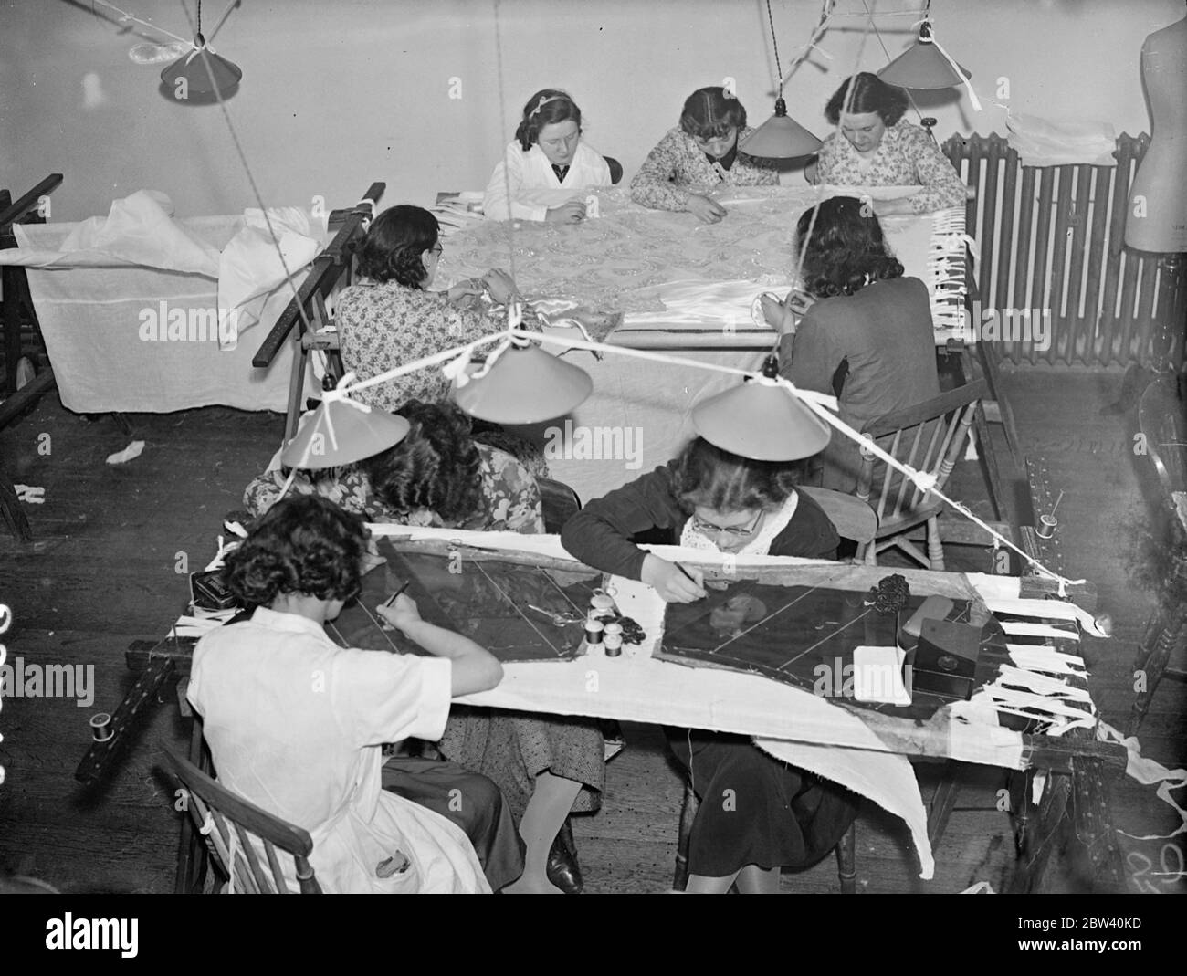 Les brodeurs de Hartnell, les couturiers de la Cour, sont à l'œuvre à Londres sur la broderie exquise pour les robes de Coronation. Les robes à porter par les six porteurs de train présents sur la Reine au Coronation sont fabriquées dans les salles Hartnell. Ils sont de conception classique fait de satin blanc duchess, brodés sur toute la longueur du front en perles dans un designer de blé. Photos : brodeurs au travail sur la broderie Coronation à Hartnell, Londres. 08 avril 1937 Banque D'Images Les brodeurs de Hartnell, les couturiers de la Cour, sont à l'œuvre à Londres sur la broderie exquise pour les robes de Coronation. Les robes à porter par les six porteurs de train présents sur la Reine au Coronation sont fabriquées dans les salles Hartnell. Ils sont de conception classique fait de satin blanc duchess, brodés sur toute la longueur du front en perles dans un designer de blé. Photos : brodeurs au travail sur la broderie Coronation à Hartnell, Londres. 08 avril 1937 Banque D'Images