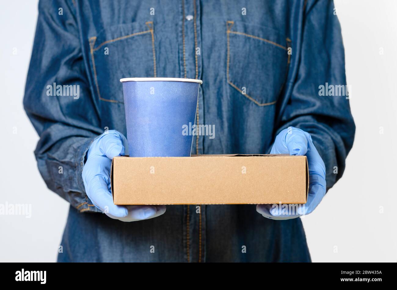 Personne avec des gants chirurgicaux qui apporte du café à la porte ou au bureau . Concept relatif à l'hygiène et à la protection contre la propagation des maladies dans les aliments Banque D'Images