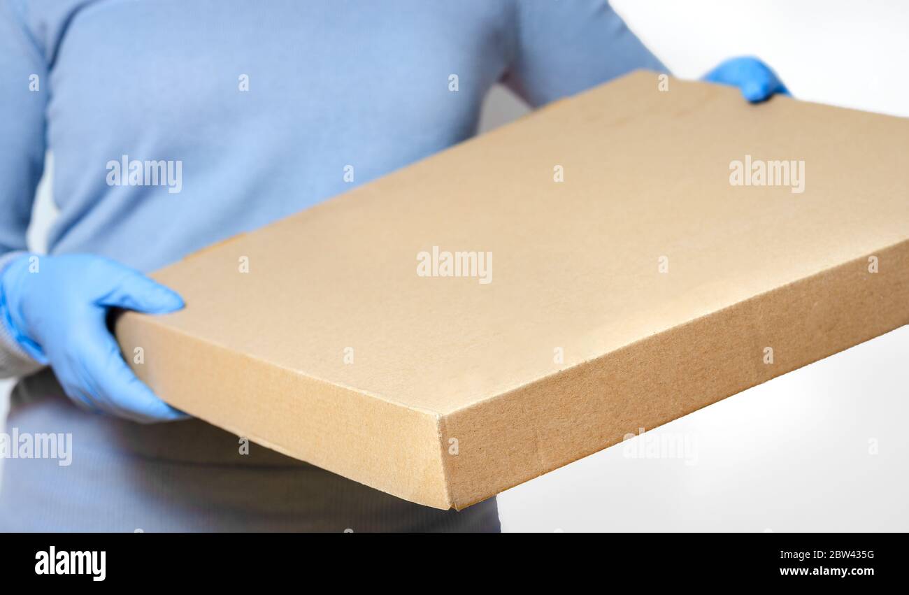 Personne avec des gants chirurgicaux qui apporte la boîte à pizza à la porte ou au bureau . Concept relatif à l'hygiène et à la protection contre la propagation des maladies en f Banque D'Images