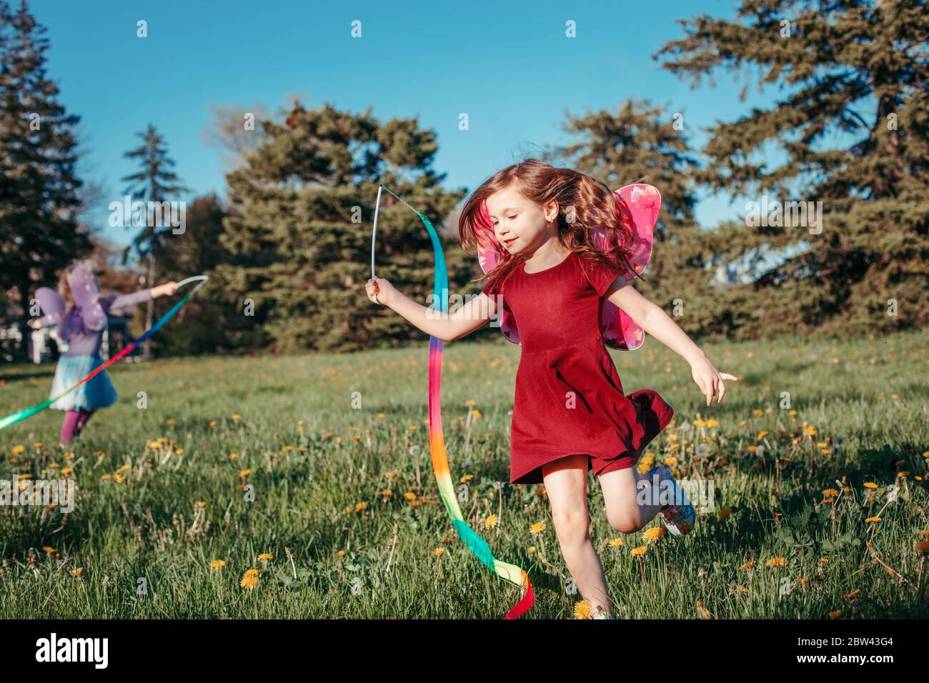 Des enfants heureux filles jouant avec des rubans dans le parc. Adorables enfants qui s'amusent dans un pré et qui jouent ensemble. Activités extérieures d'été dans la cour pour les enfants. H Banque D'Images