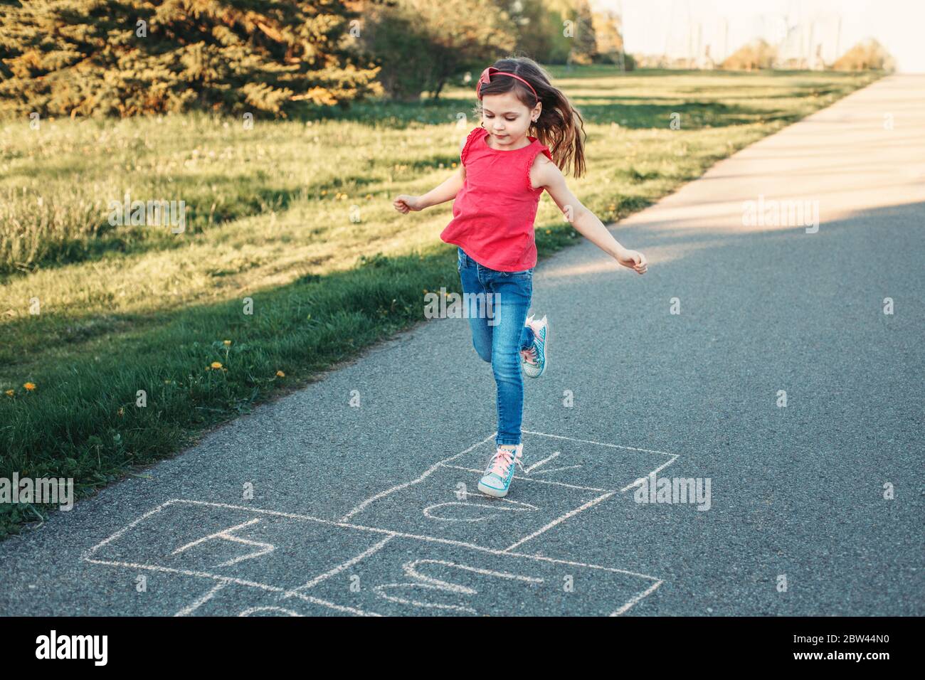 Adorable adorable adorable petite fille fille jouant à hopscotch en plein  air. Jeu d'activités amusant pour les enfants sur l'aire de jeux à  l'extérieur. Sports de rue d'arrière-cour d'été pour Photo Stock -