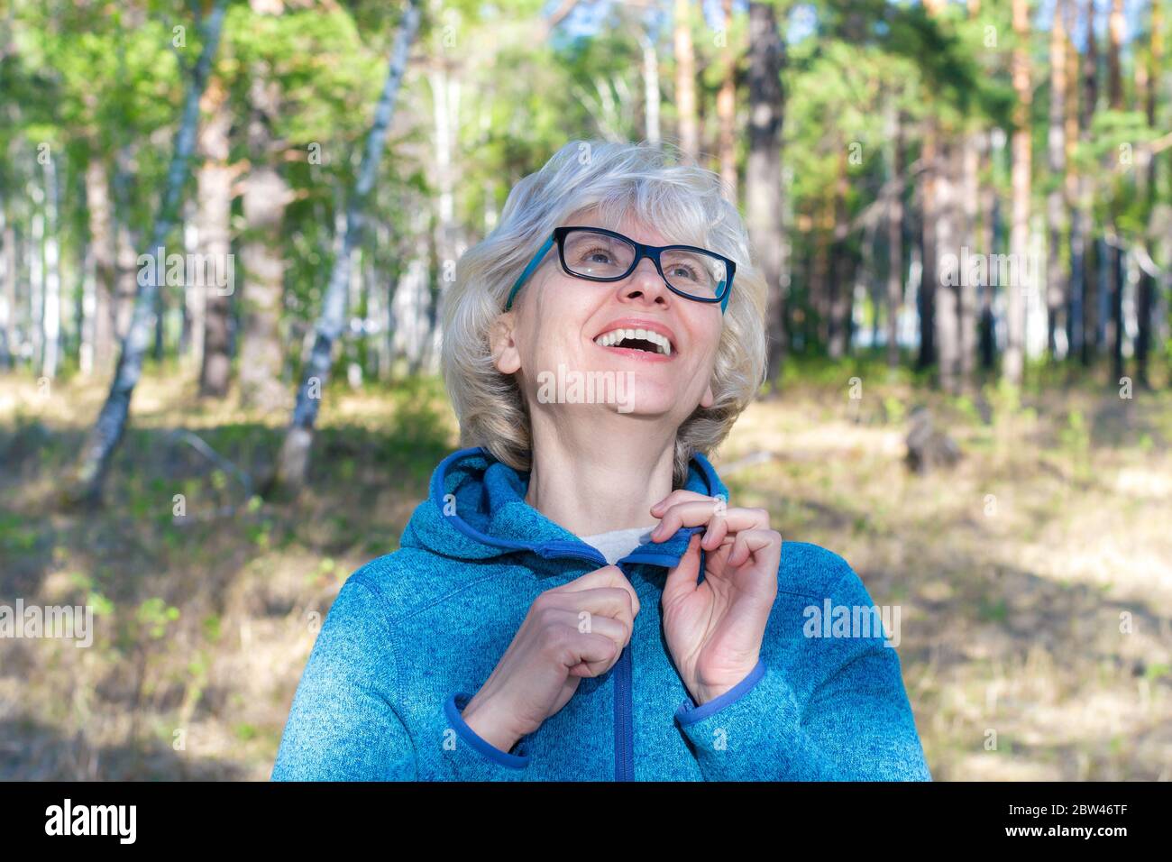 Rire de la femme d'âge moyen avec des lunettes marchant dans le parc. Jour d'été ensoleillé. Le concept de liberté et de joie. Banque D'Images