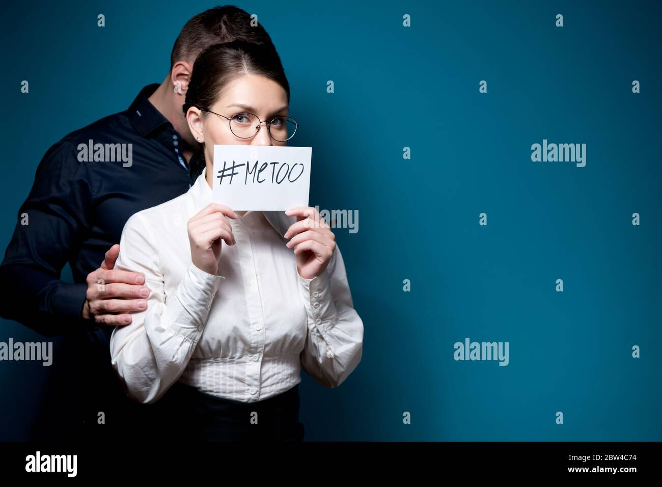une femme porte un signe avec une inscription metoo, et derrière elle se trouve une silhouette d'homme dans une obscurité Banque D'Images