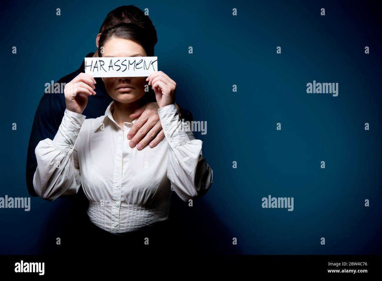 la fille ferme les yeux avec un morceau de papier avec l'inscription harcèlement, derrière elle est un homme Banque D'Images