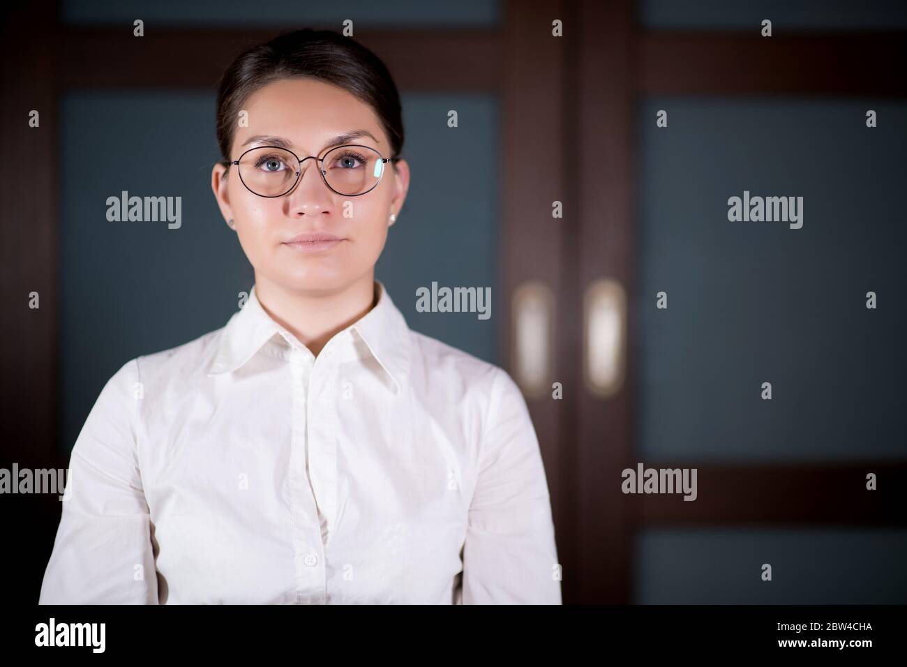 la fille en lunettes et une chemise regarde calmement dans devant elle Banque D'Images