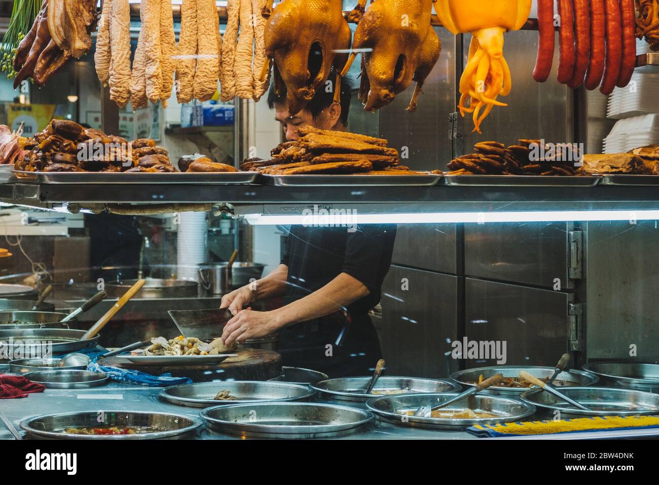 Hong Kong - novembre 2019 : le chef du restaurant chinois prépare la nourriture derrière la fenêtre du magasin Banque D'Images