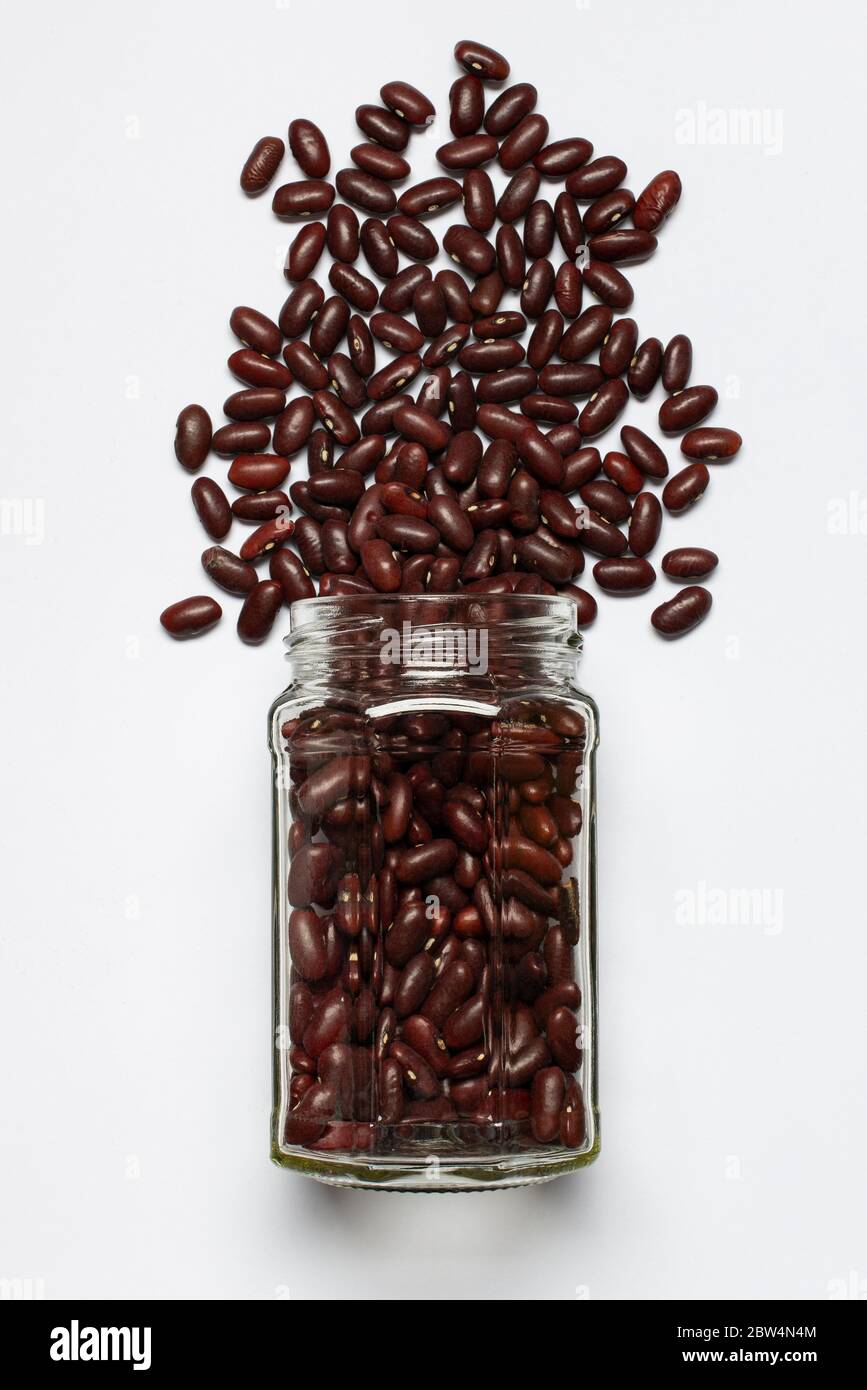 bocal en verre avec haricots rouges au premier plan, vue de dessus, isolé du fond blanc Banque D'Images