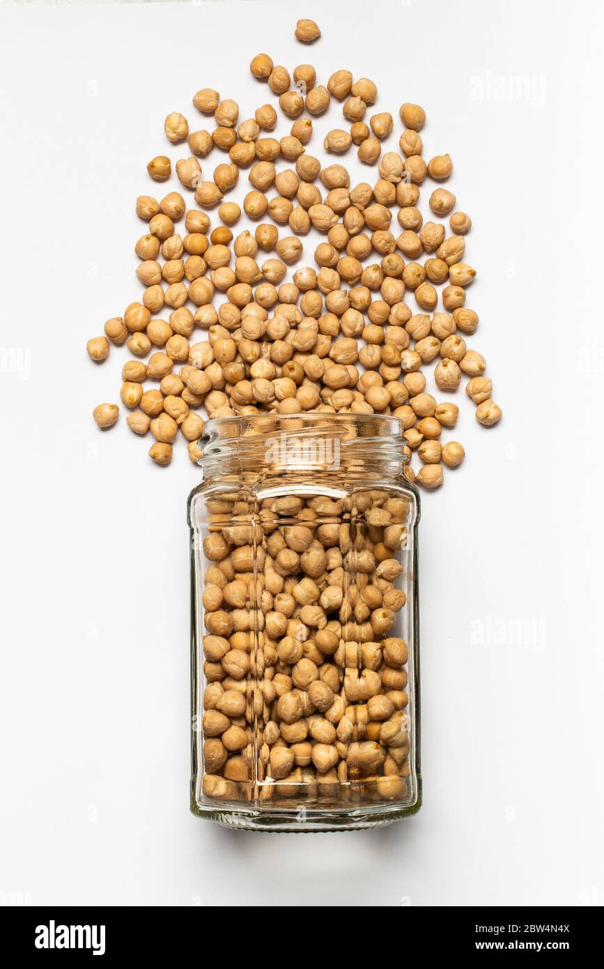 pot en verre avec pois chiches séchés au premier plan, vue de dessus, isolé du fond blanc Banque D'Images