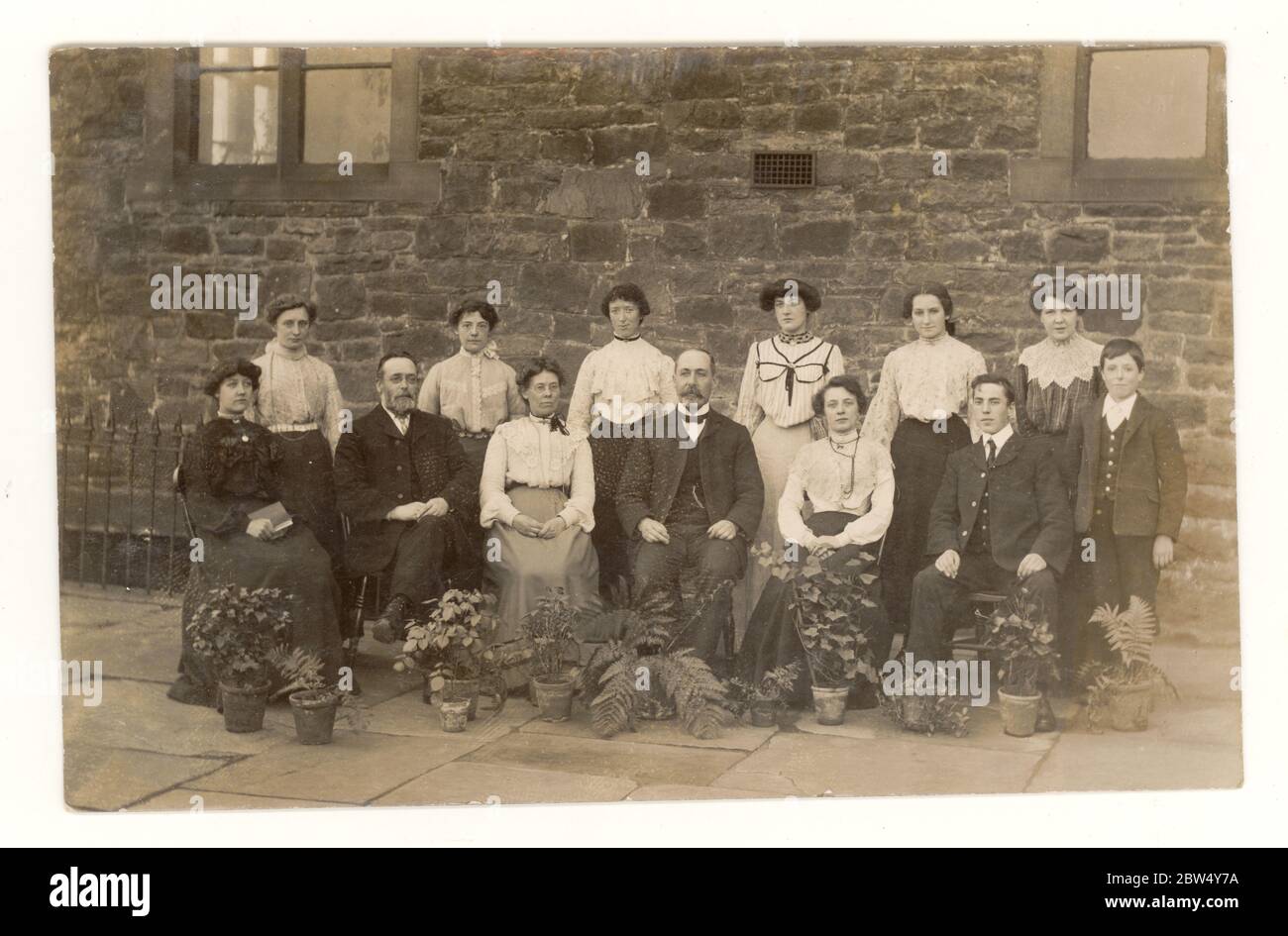 Carte postale Edwardienne originale du début des années 1900, représentant des travailleurs élégants de Blackburn, peut-être des employés de bureau de l'usine de coton, qui posaient à l'extérieur de leur bureau, avec des pots de fleurs, publiée le 27 septembre 1904, Blackburn, Lancashire, Angleterre, Royaume-Uni Banque D'Images