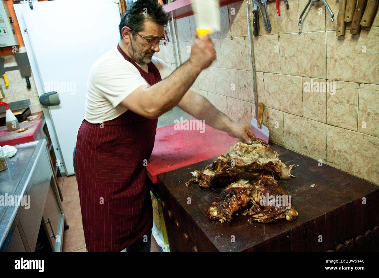 Un cuisinier grec local hacher des chèvres grillées dans un restaurant du village local dans la ville de Profitis Ilias sur l'île de Samothraki, Thrace, Grèce. Banque D'Images