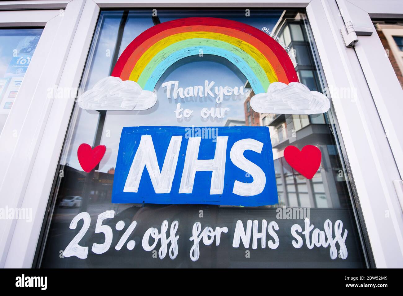 Des fenêtres récemment peintes, Merci NHS et un arc-en-ciel ont été peints sur un front de boutique à Manchester pour remercier tout le personnel de première ligne NHS. Banque D'Images