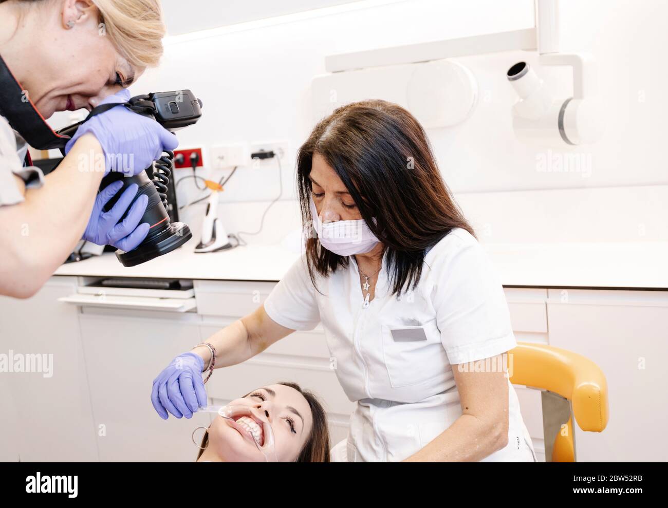 Dentiste photographiant la bouche d'une jeune patiente alors que l'infirmière tient sa bouche ouverte Banque D'Images