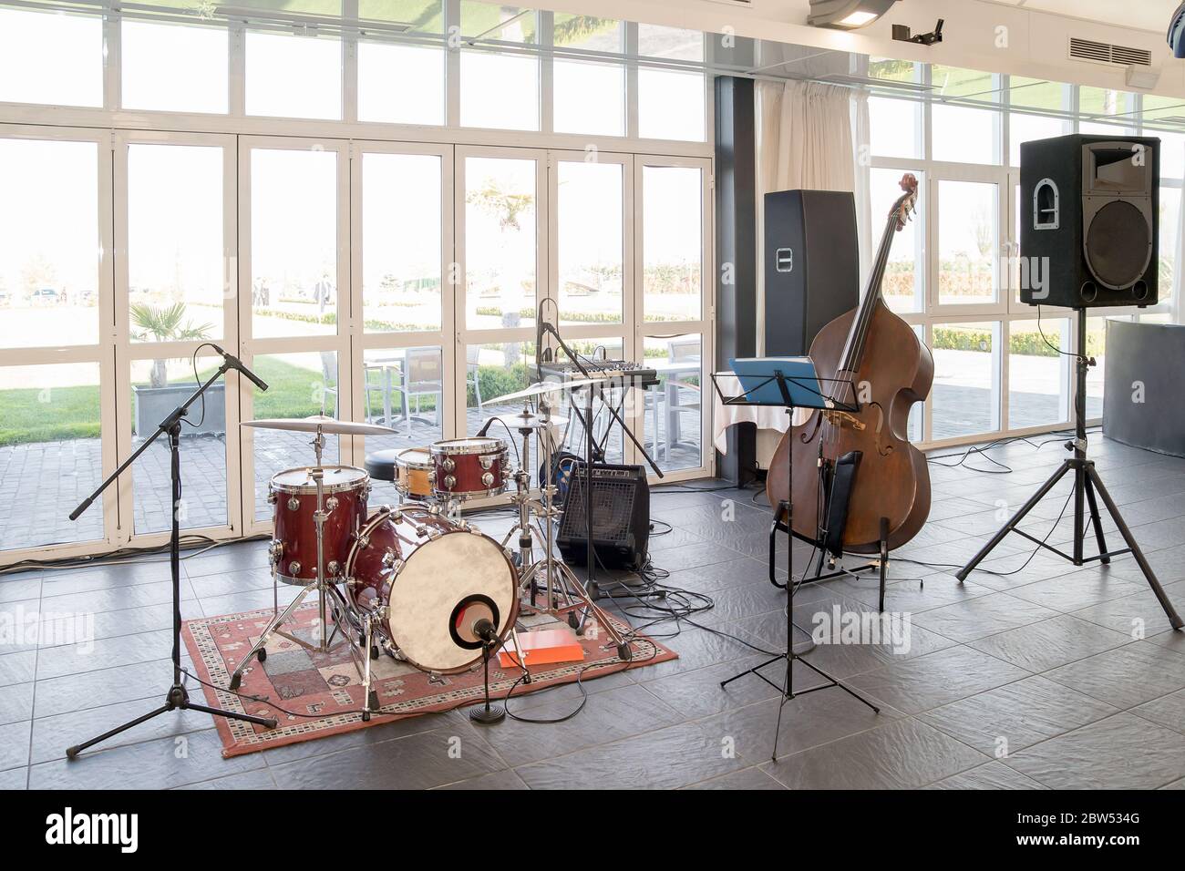 Instruments de musique, double basse à côté d'une batterie, haut-parleurs et microphones dans une pièce par beau temps. Banque D'Images