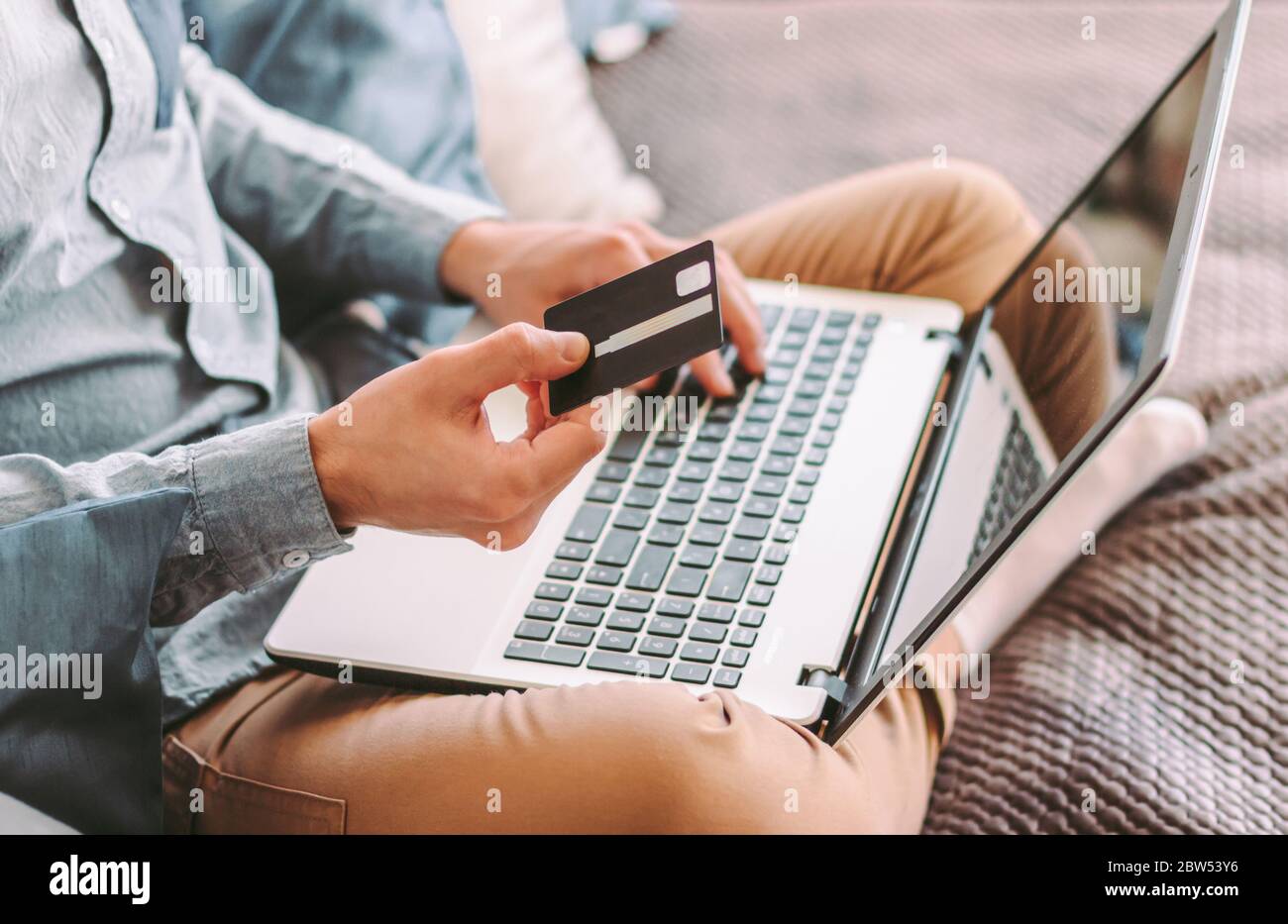 Gros plan jeune hippster mâle tient carte de crédit et de type sur clavier d'ordinateur portable, shopping en ligne, travailler à la maison. Homme de style indépendant à l'aide de comput Banque D'Images