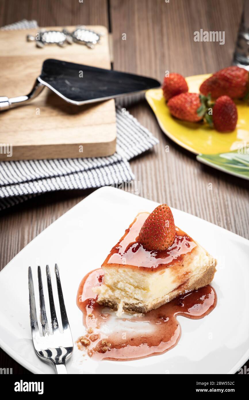 une délicieuse tranche de fraises cheesecake sur une assiette blanche sur une table en bois Banque D'Images