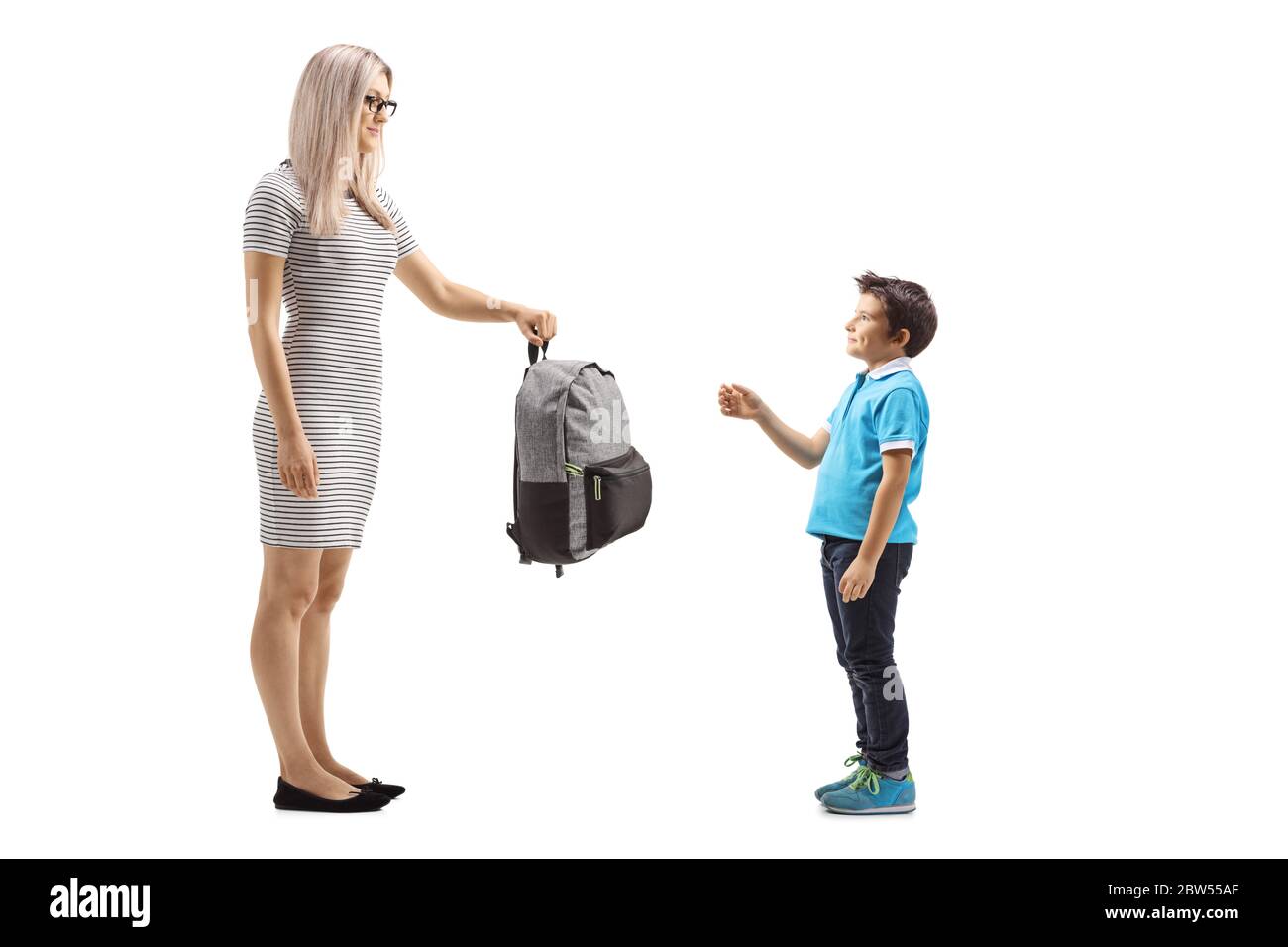 Photo en longueur d'une mère donnant un sac à dos à un garçon isolé sur fond blanc Banque D'Images