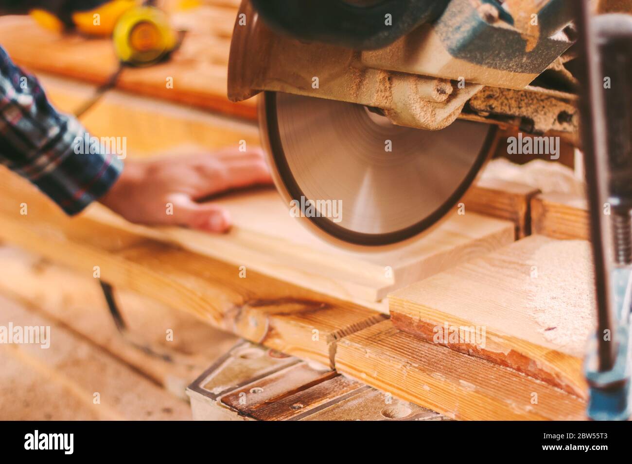 Gros plan d'un menuisier professionnel travaillant avec une scie circulaire électrique dans un atelier de travail du bois. Fabricant d'armoires homme qualifié utilisant une scie circulaire pour couper sans Banque D'Images