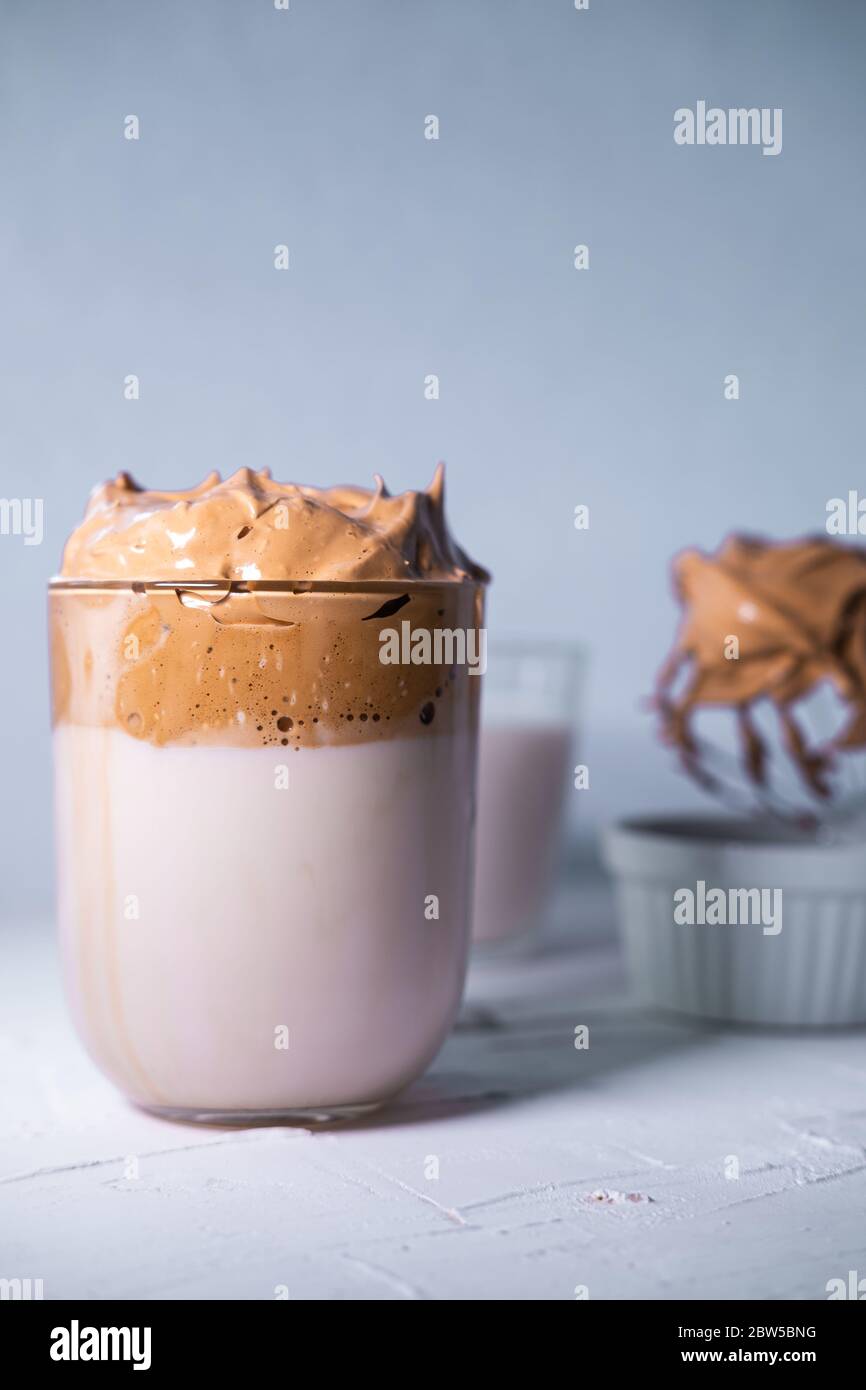 Café Dalgona au lait dans un verre sur fond blanc texturé. Café coréen. Vue rapprochée. Banque D'Images