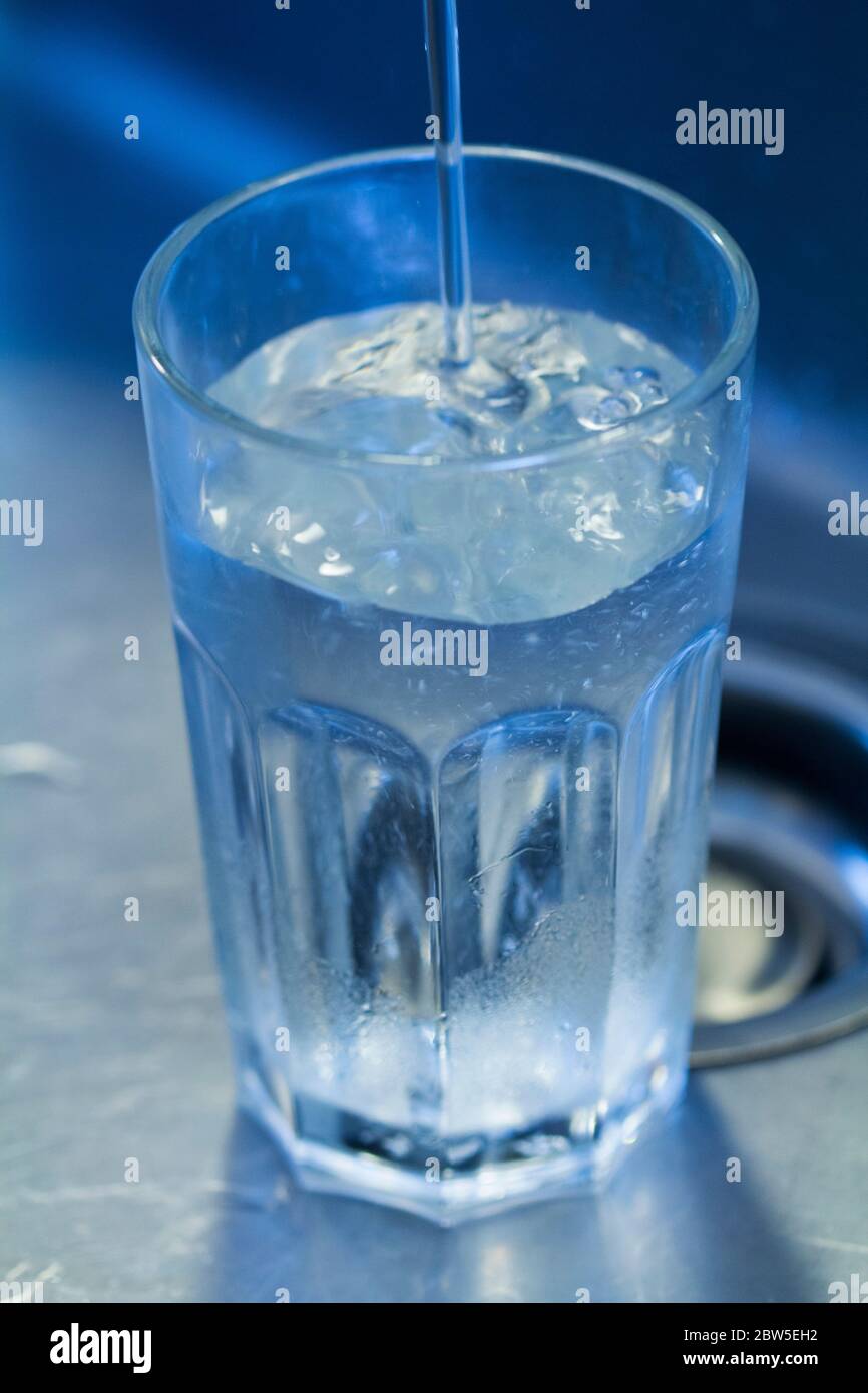 Verre rempli d'eau du robinet dans un évier. Banque D'Images