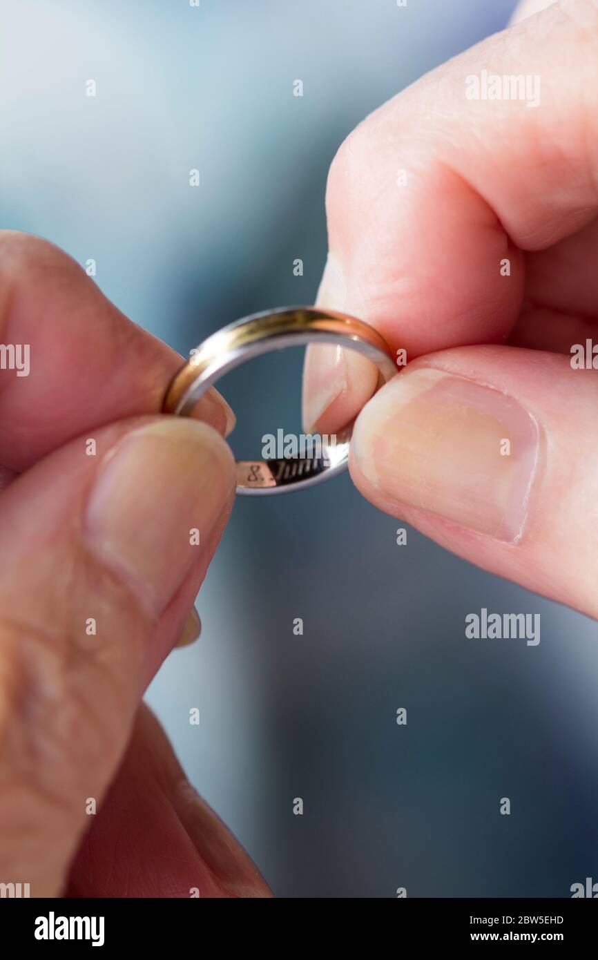 Gros plan des mains tenant un anneau de mariage inscrit avec une date. Banque D'Images