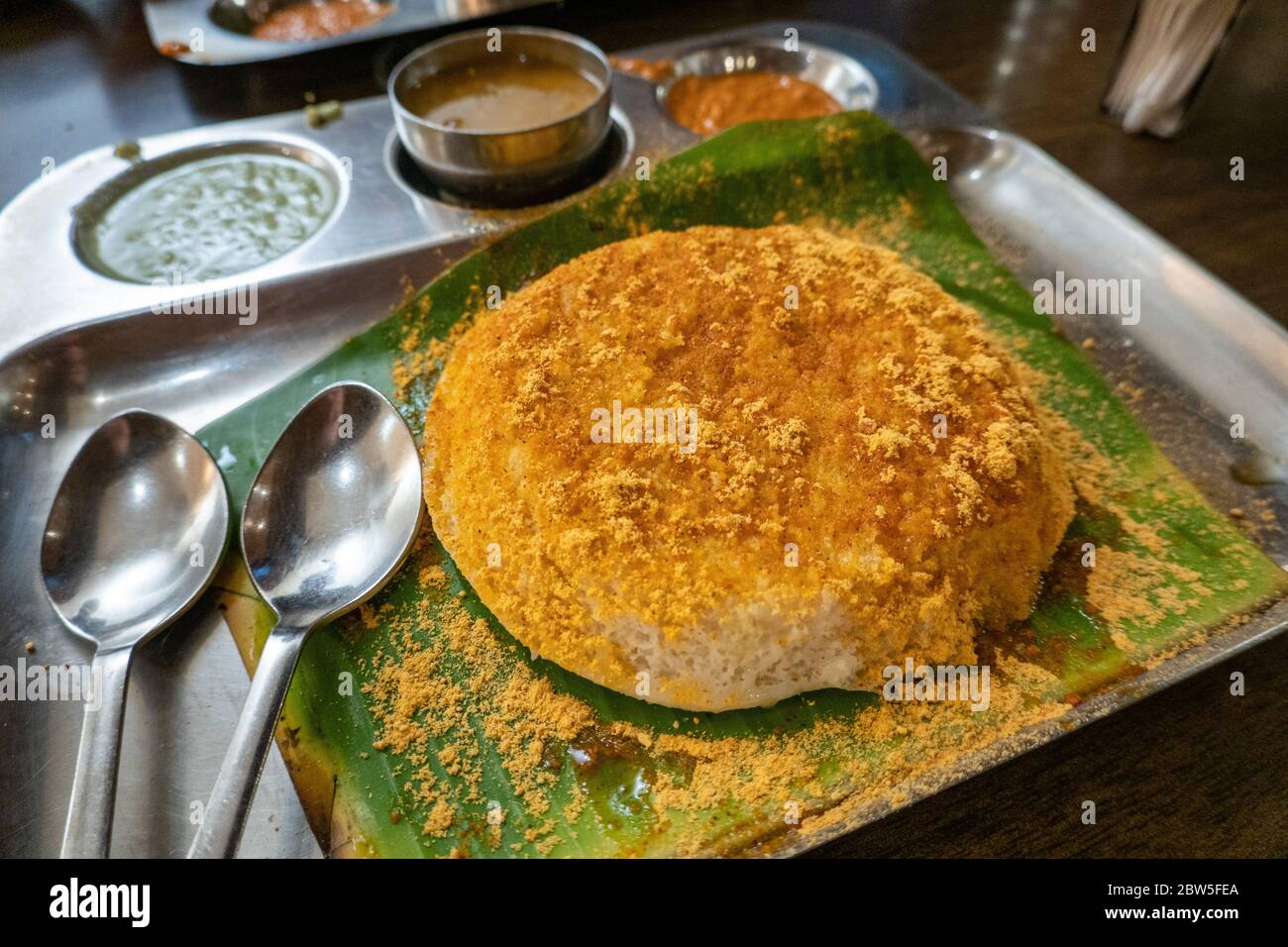 Un grand thattu idli (gâteau au riz cuit à la vapeur) servi avec des chutneys au restaurant Eating Circles à Chennai, Inde Banque D'Images