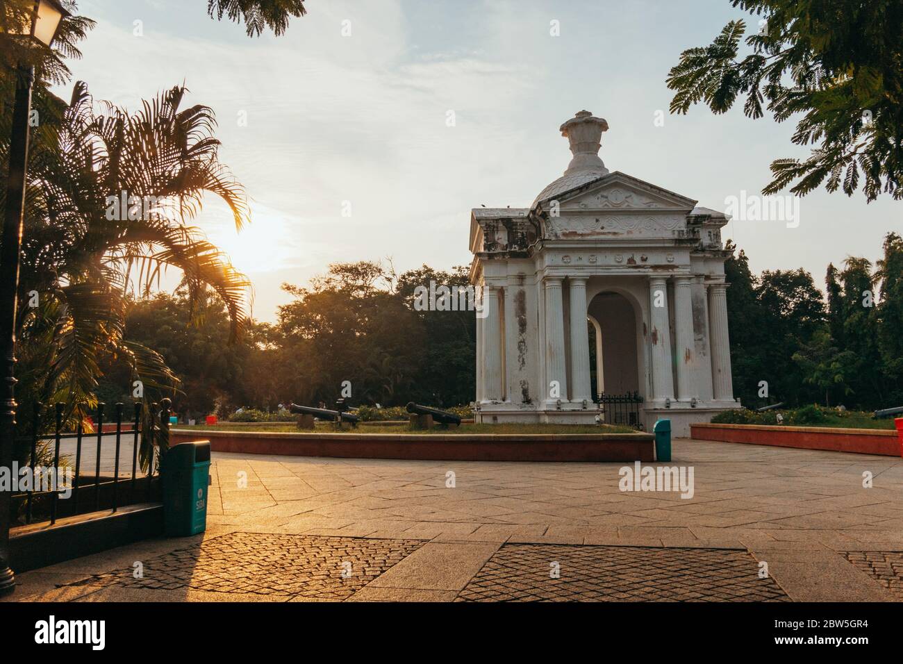 Le soleil se couche derrière une arche gréco-romaine dans le centre du parc Bharathi, Pondichéry, Inde Banque D'Images