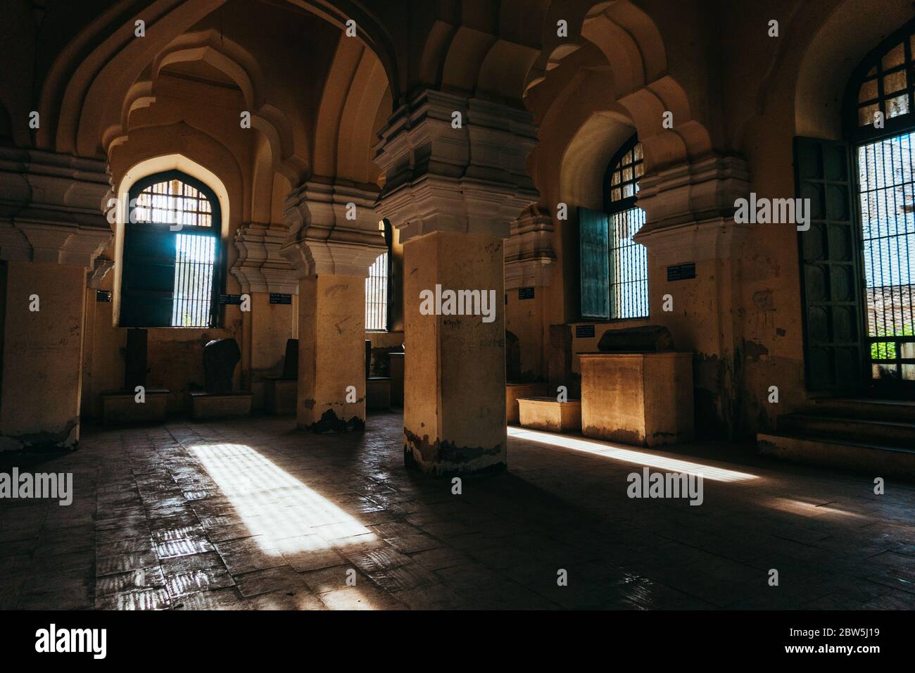 La lumière du soleil traverse des fenêtres dans les coins plus sombres du palais Thirumalai Nayakkar, Madurai, Inde Banque D'Images