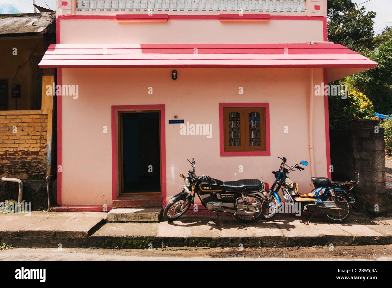 Une petite maison rose vif à Kumily, en Inde, avec deux motos garées devant Banque D'Images