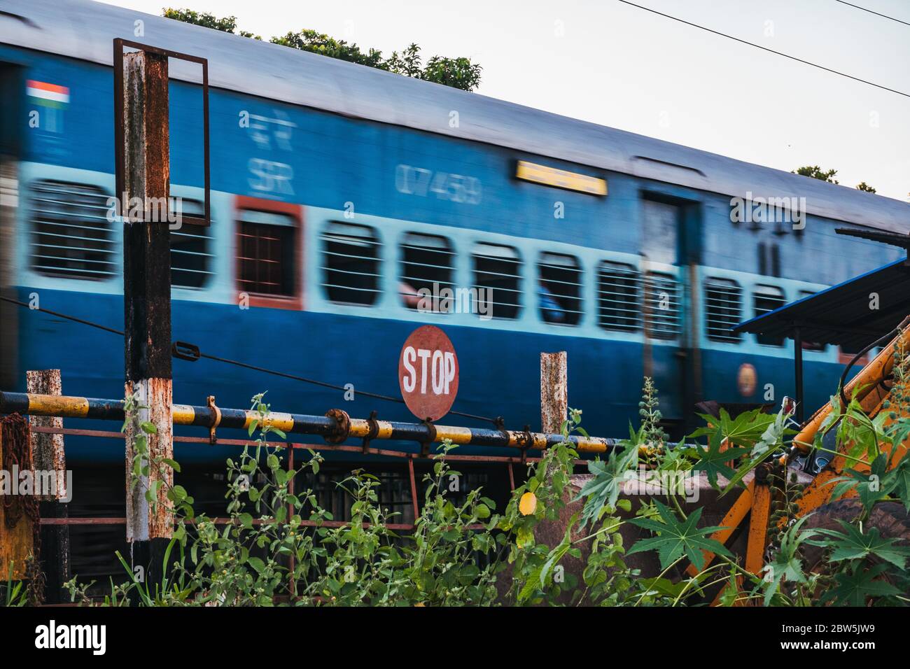 Un train de voyageurs passe devant un panneau d'arrêt à un passage à niveau de chemin de fer à Alappuzha, Kerala, Inde Banque D'Images