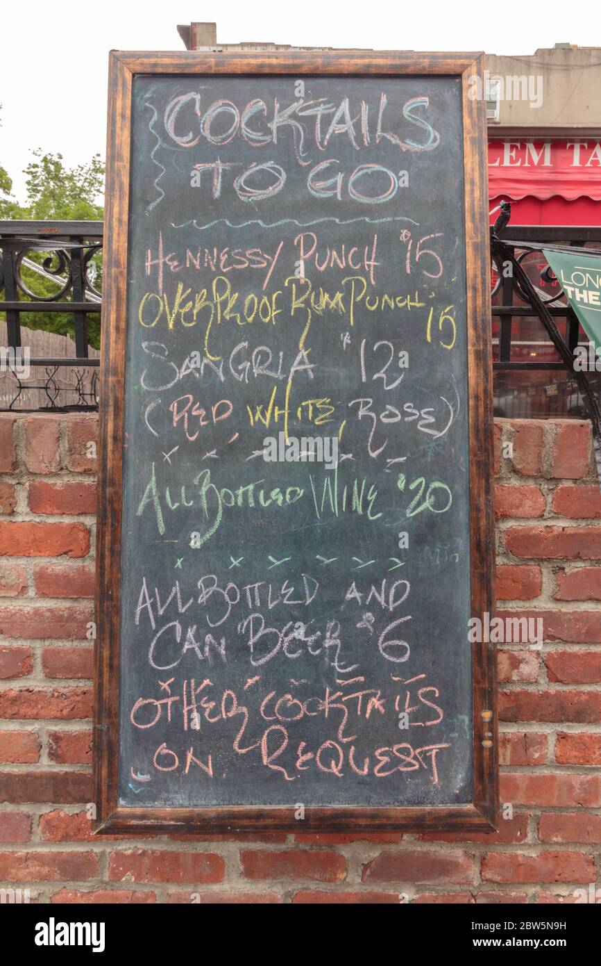 Un panneau noir ou tableau noir en face de la taverne Harlem répertorie le menu des cocktails qu'elle propose pendant la pandémie du coronavirus ou du covid-19 Banque D'Images