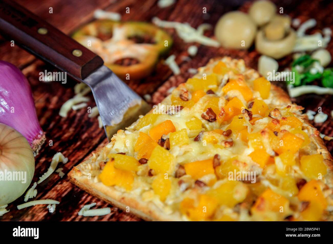 Gros plan d'une demi-tranche de pizza aux saveurs contrastées avec ananas, mangue et saucisse chaude nappée de fromage mozzarella Banque D'Images