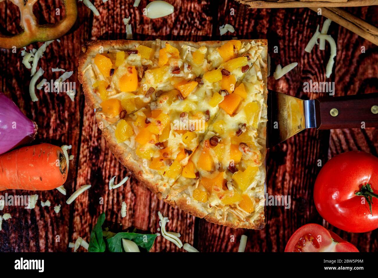 Vue du dessus photo inversée de délicieux pizza douce et épicée avec ananas, mangue, saucisse chaude et fromage mozzarella entouré de légumes frais Banque D'Images